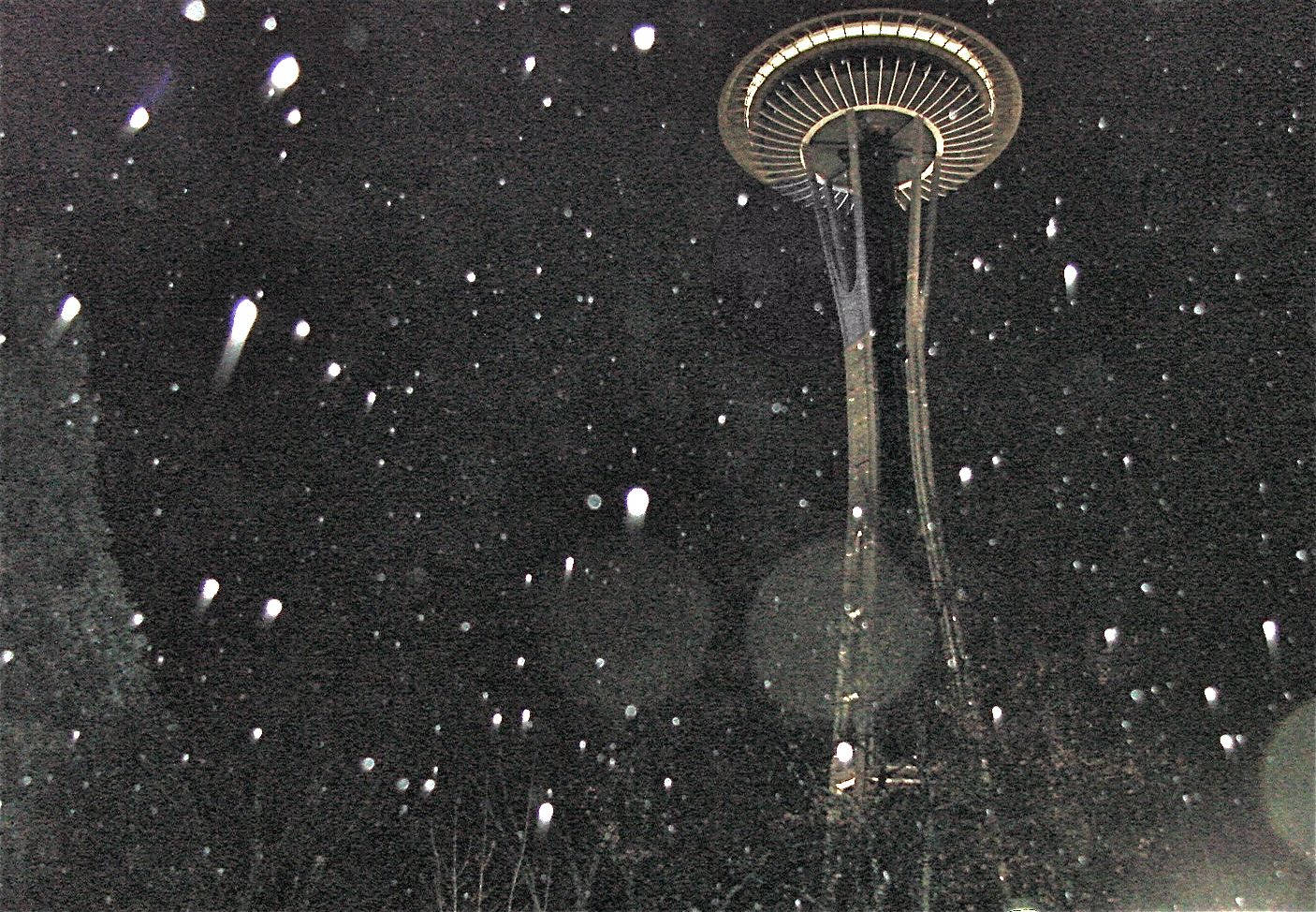 西雅圖夜晚，燈火通明的太空針塔周圍飄雪。