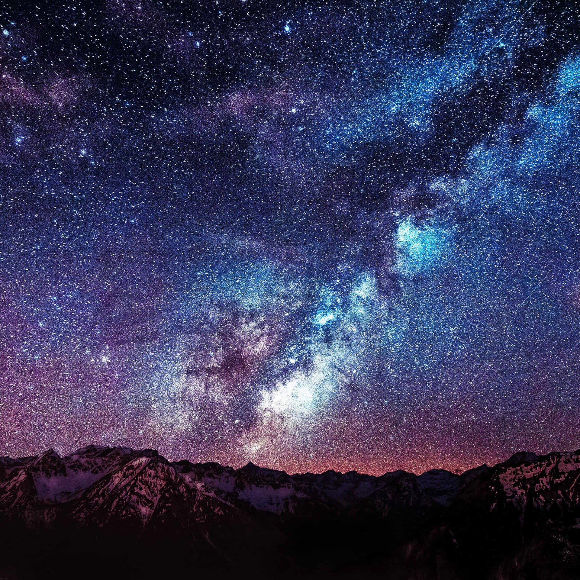 在生動星空下，積雪的山峰與發光的宇宙雲。