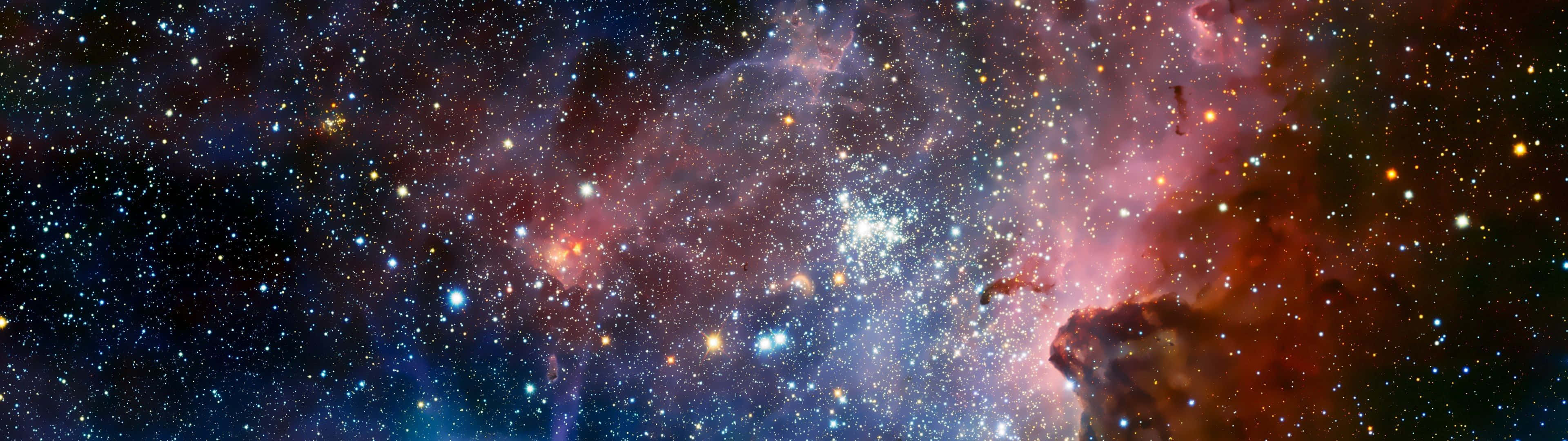 太空高清 3840x1080 銀河 壁紙 — 一個令人嘆為觀止的宇宙全景，展示出在星空中閃耀著紅色、紫色和藍色的鮮豔星雲。