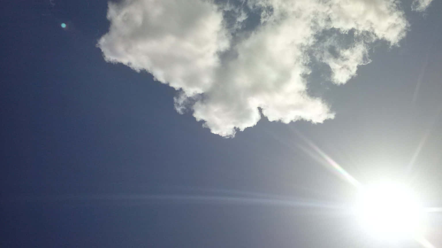 太陽穿過白雲在藍天中帶有鏡頭光暈