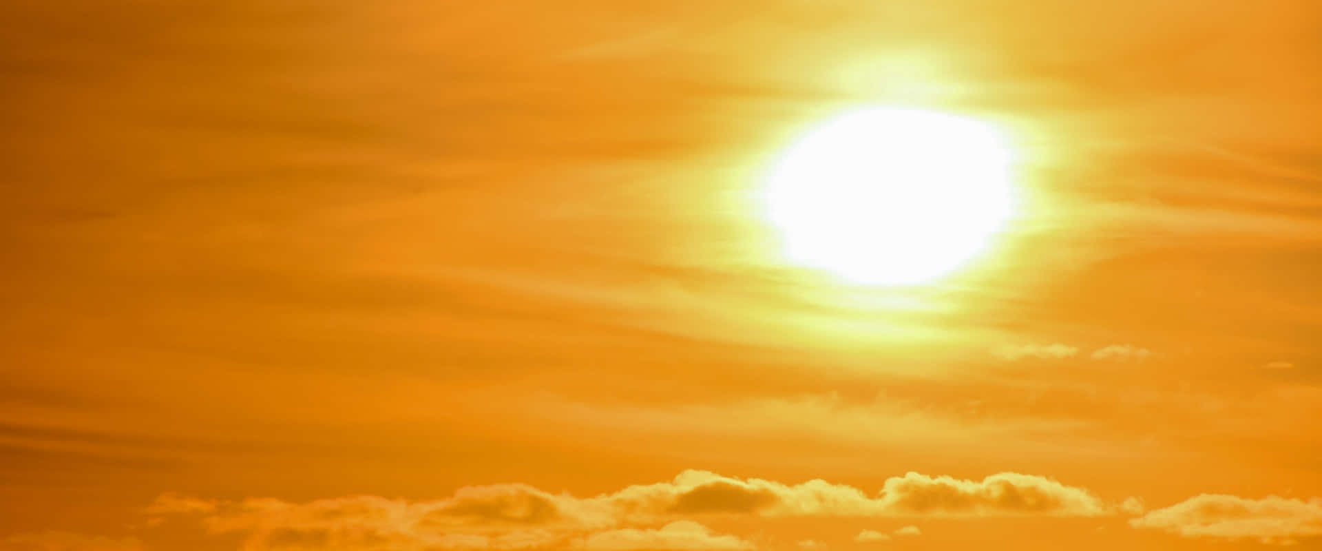 太陽在橙色天空中明亮地照耀，伴隨著柔和的雲朵