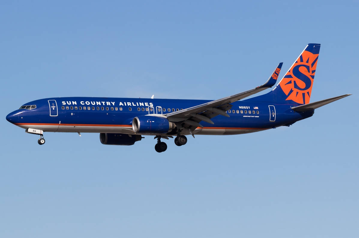 Sun Country Airlines 飛機在晴朗的藍天下飛行，起落架已放下