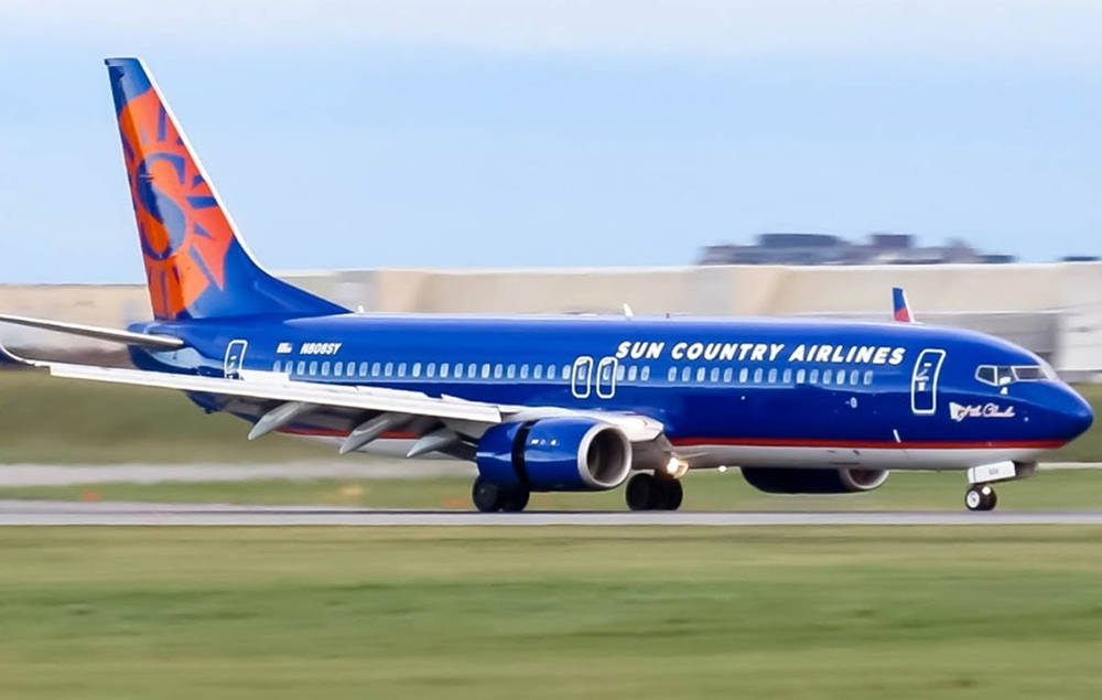 藍色和橙色的 Sun Country Airlines 噴射機在跑道上滑行。