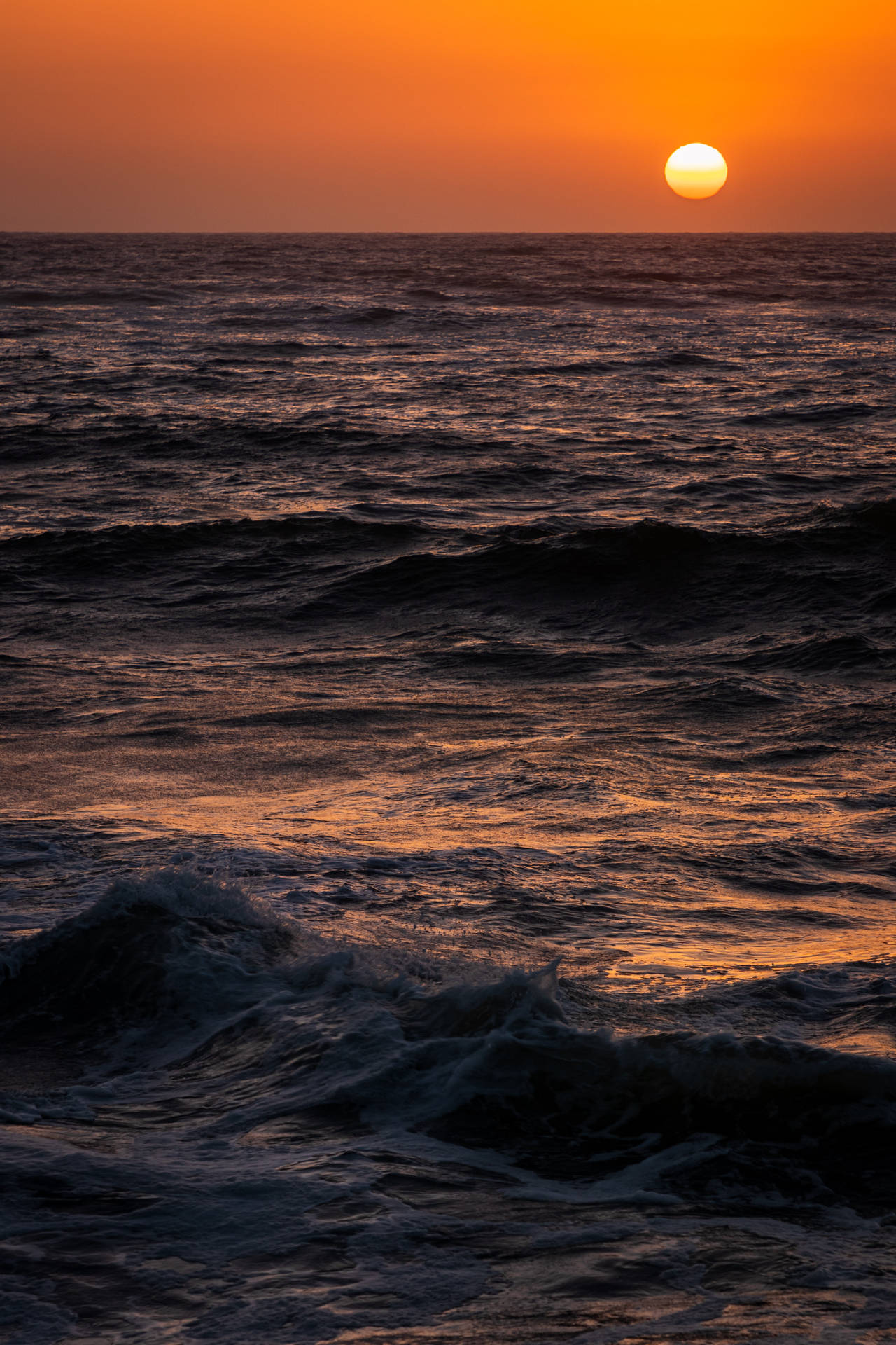 海上日落，波浪上泛著橙色光芒