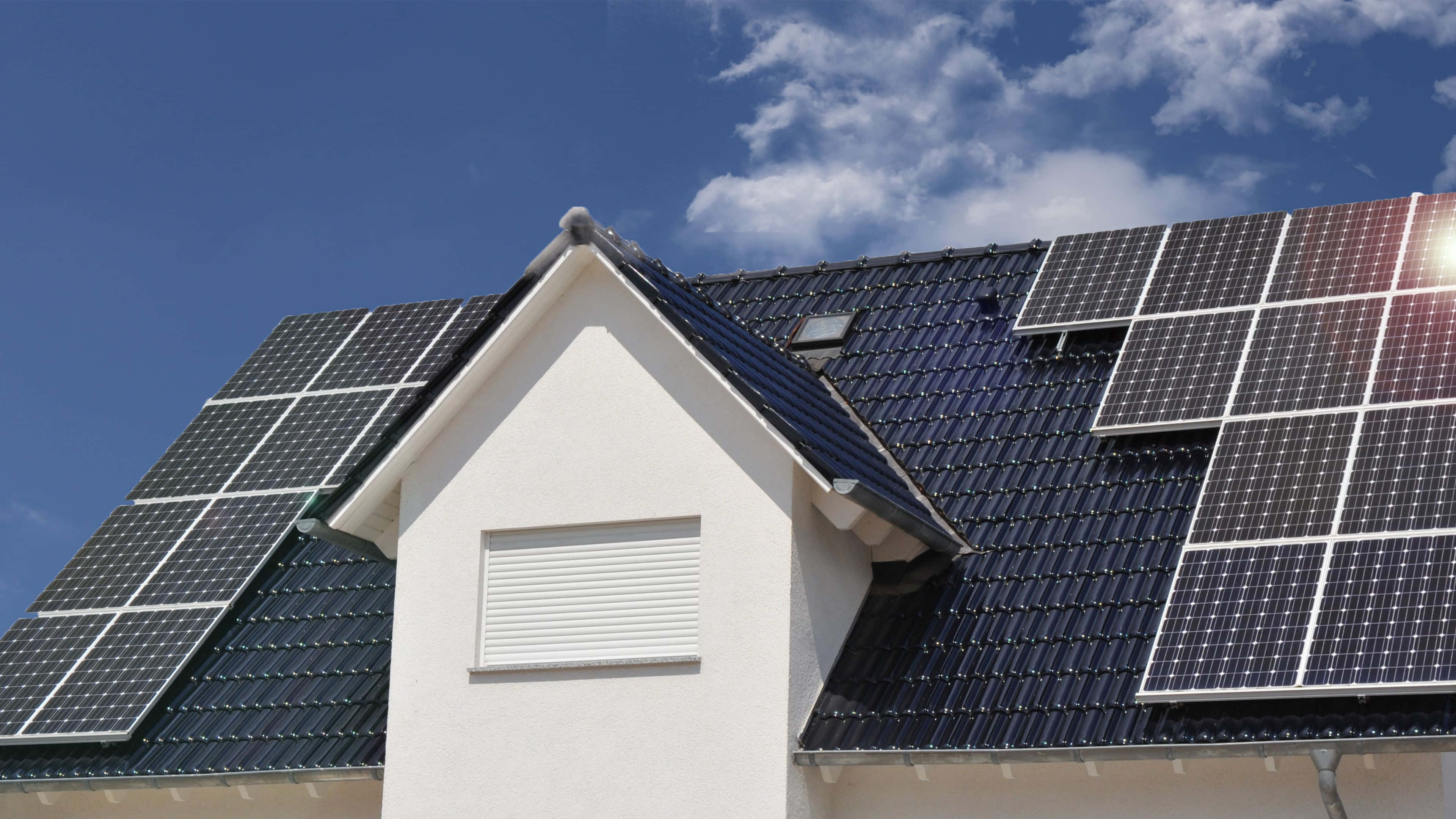 Solar Panel 桌布 壁紙 — 太陽能板在藍天白雲下嘅住宅屋頂上閃閃發光。