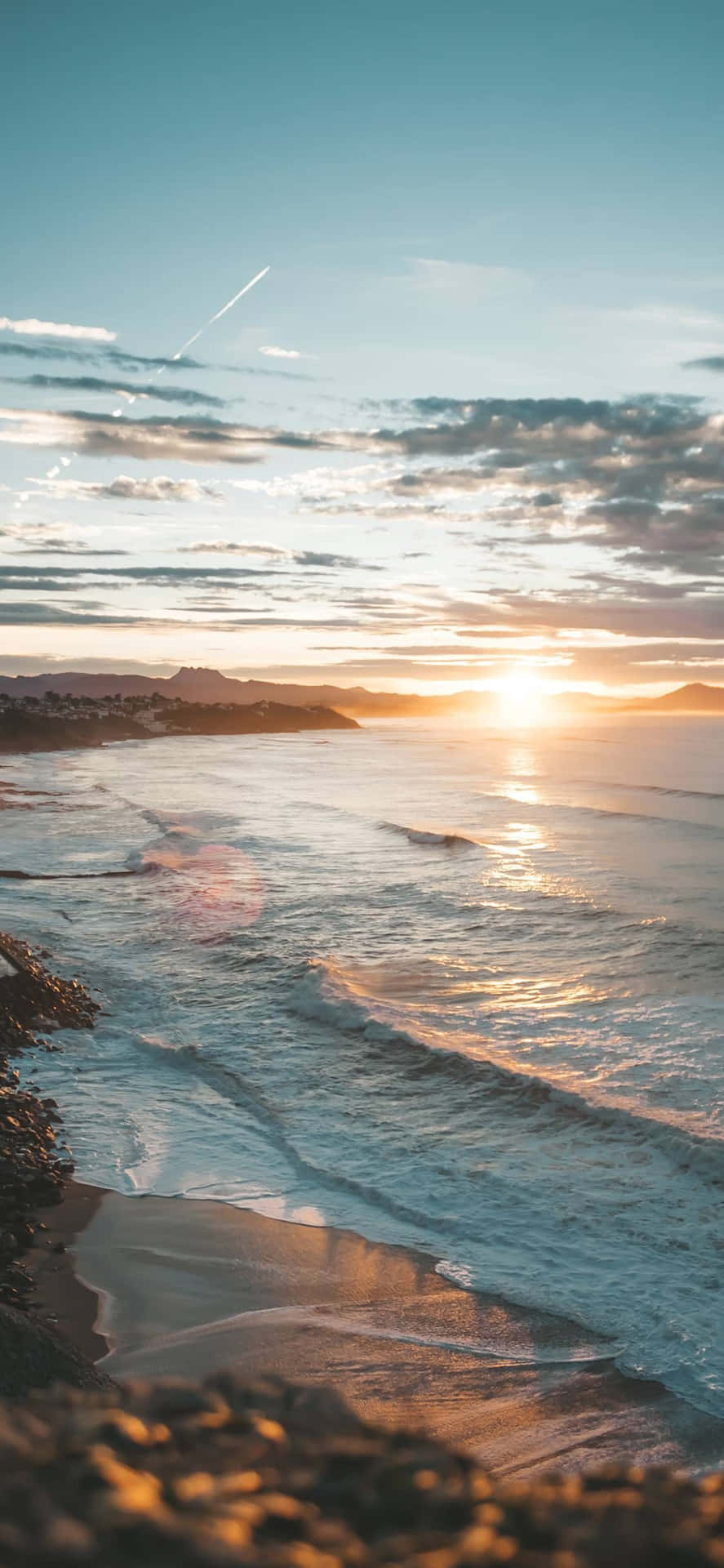 夕陽照耀在海浪上，岩石海灘，遠山