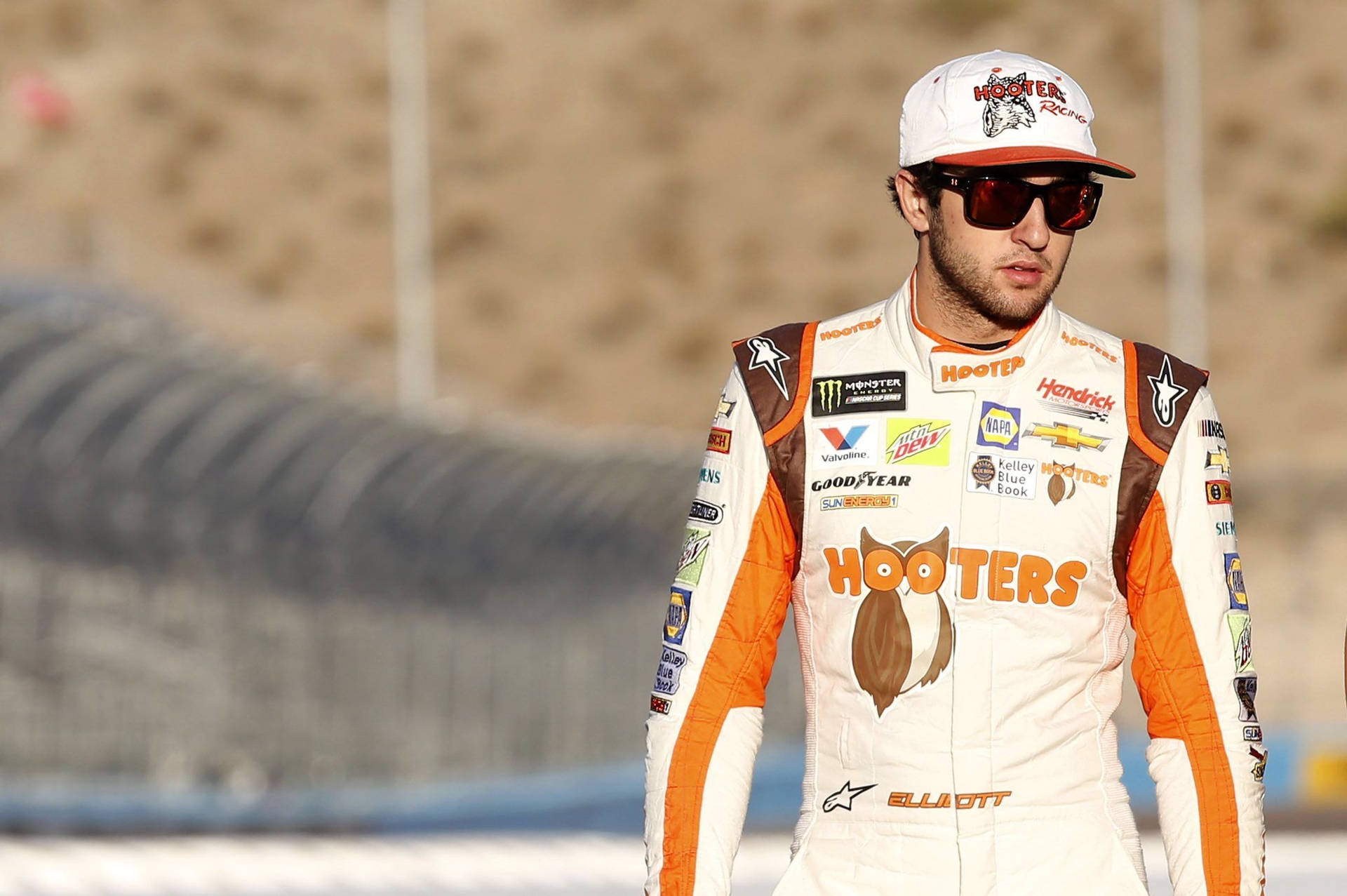 NASCAR車手穿著Hooters賽車服在賽道上，背景是沙漠。