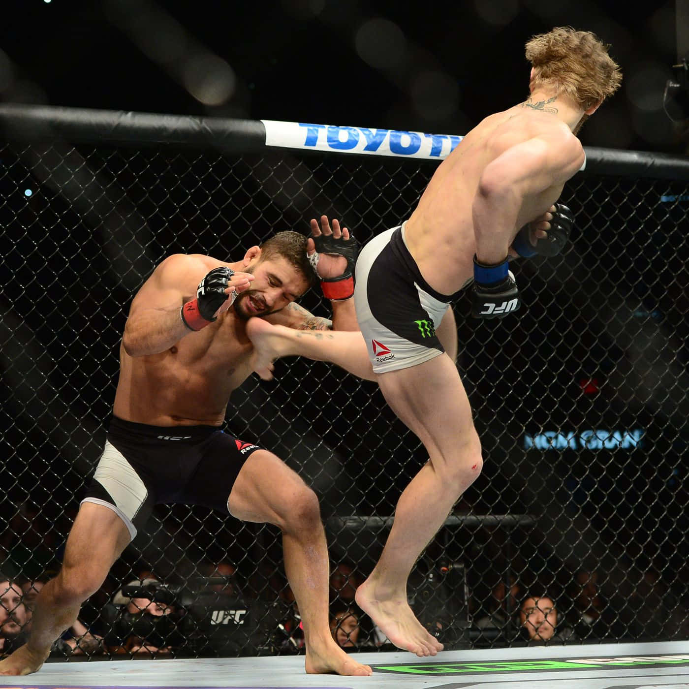 兩名MMA拳手在UFC八角籠內交戰，其中一人使出高踢。