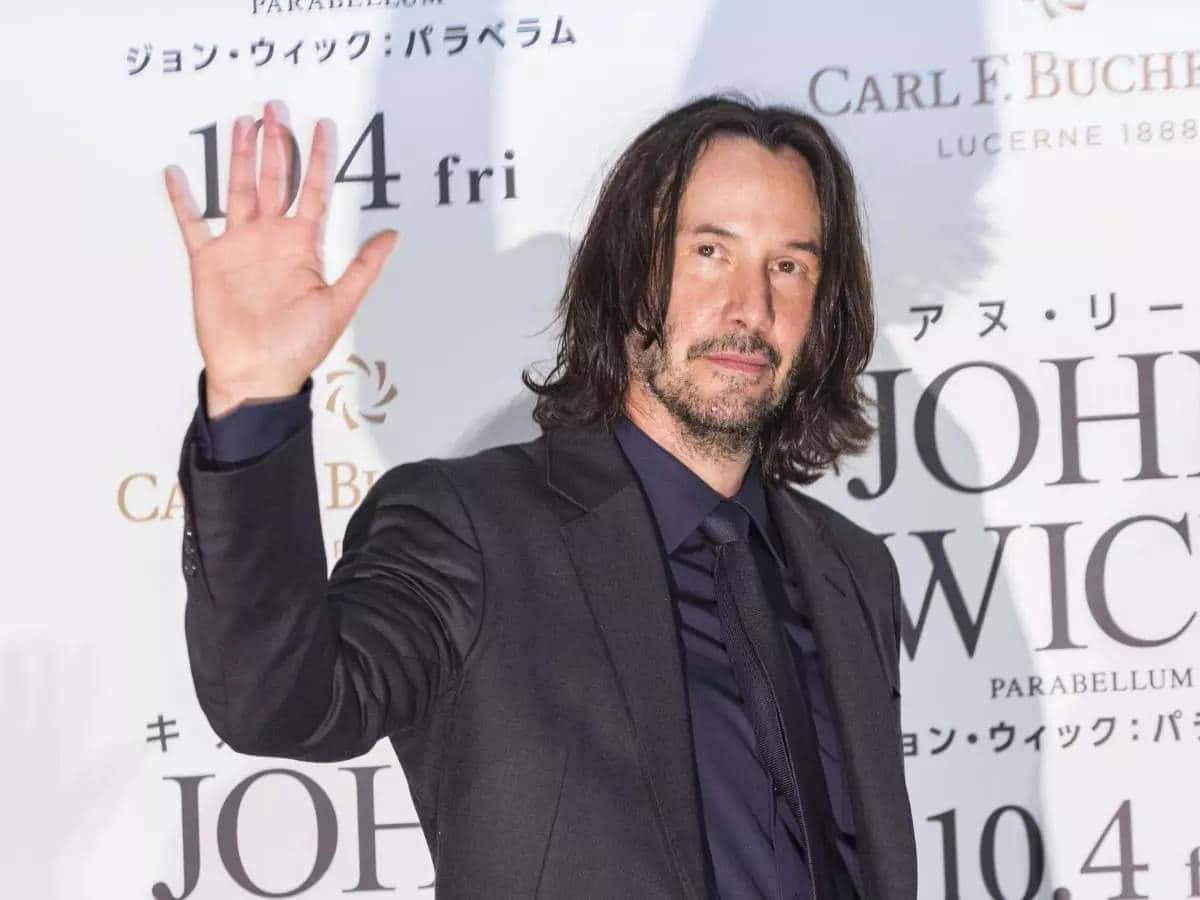 Keanu Reeves 桌布 壁紙 — 奇洛·李維斯在《殺神John Wick》電影首映禮上向鏡頭揮手，背後有宣傳文字。