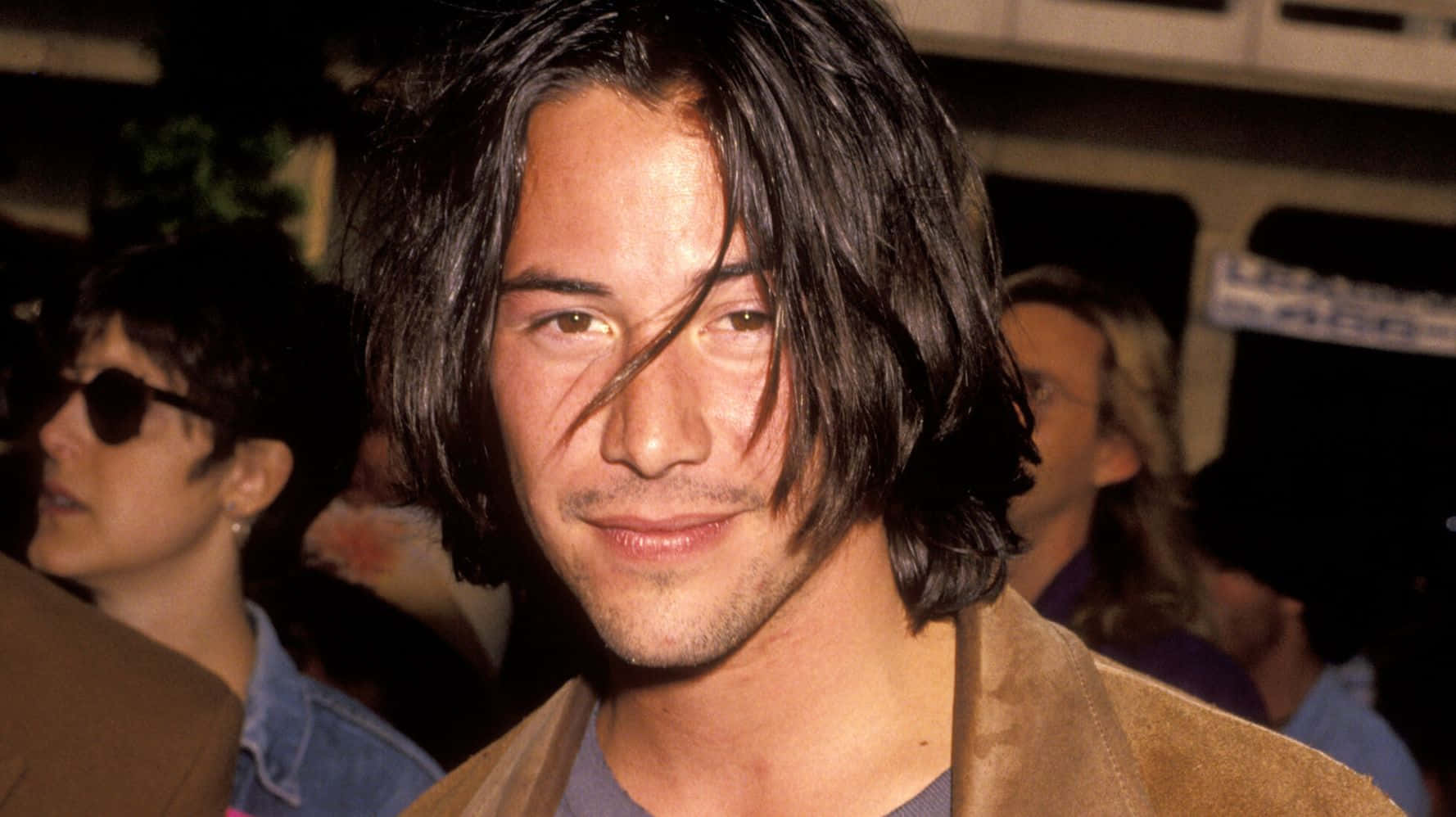 Keanu Reeves 桌布 壁紙 — 奇洛李維斯一頭凌亂黑髮，帶著微妙微笑，在一張坦率的夜間照片中直視鏡頭。