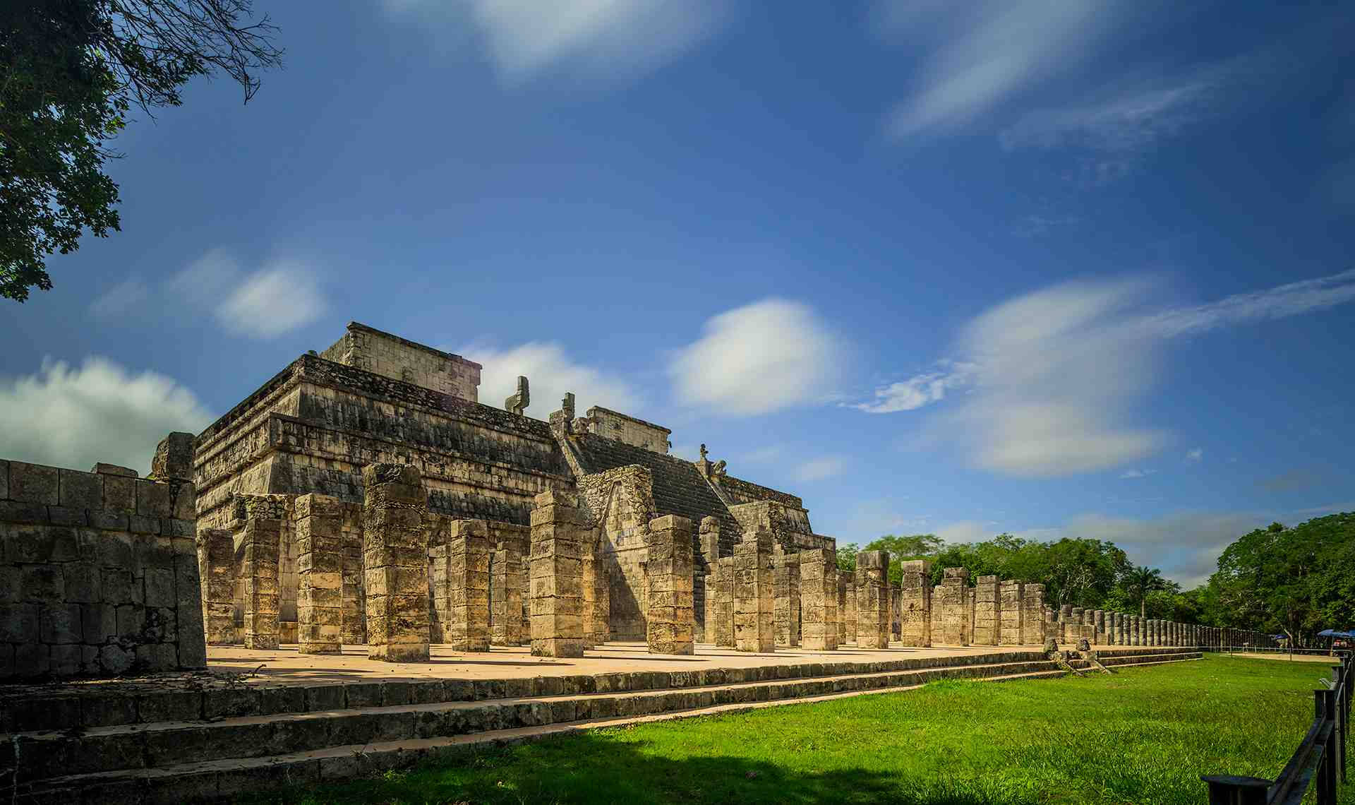 奇琴伊察古代遺跡 壁紙 — 古老的瑪雅石廟群在明亮的藍天、蓬鬆的白雲和茂盛的綠草下巍然聳立。