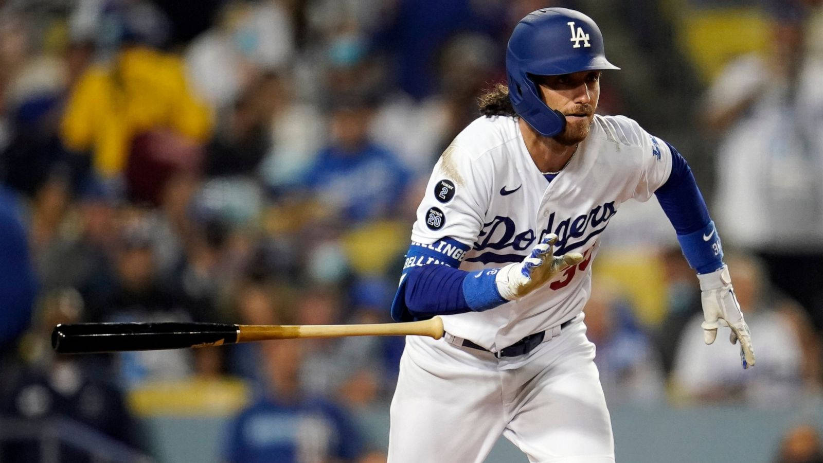奔跑中的 Cody Bellinger 專注攝影 壁紙 — 身穿道奇隊球衣的棒球選手在球場燈光下專注地揮棒擊球。