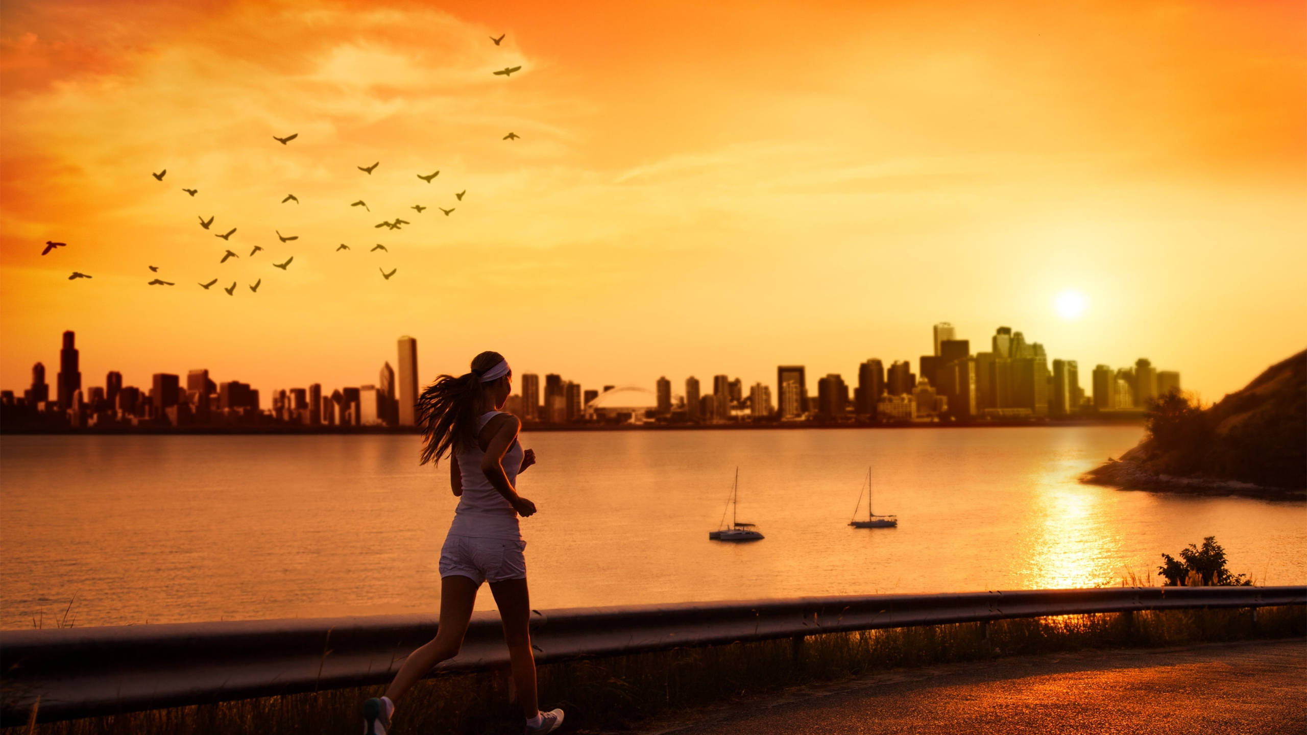 奔跑的女子夕陽 壁紙 — 一名女子在日落時沿著海濱小徑跑步，背景是城市天際線和帆船。