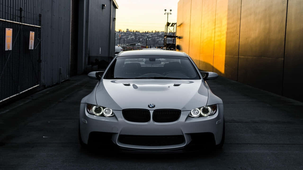 奢華BMW置身如畫戶外風景 壁紙 — 一架時尚的銀色寶馬M3跑車停泊在沐浴著金色日落光線的小巷中。