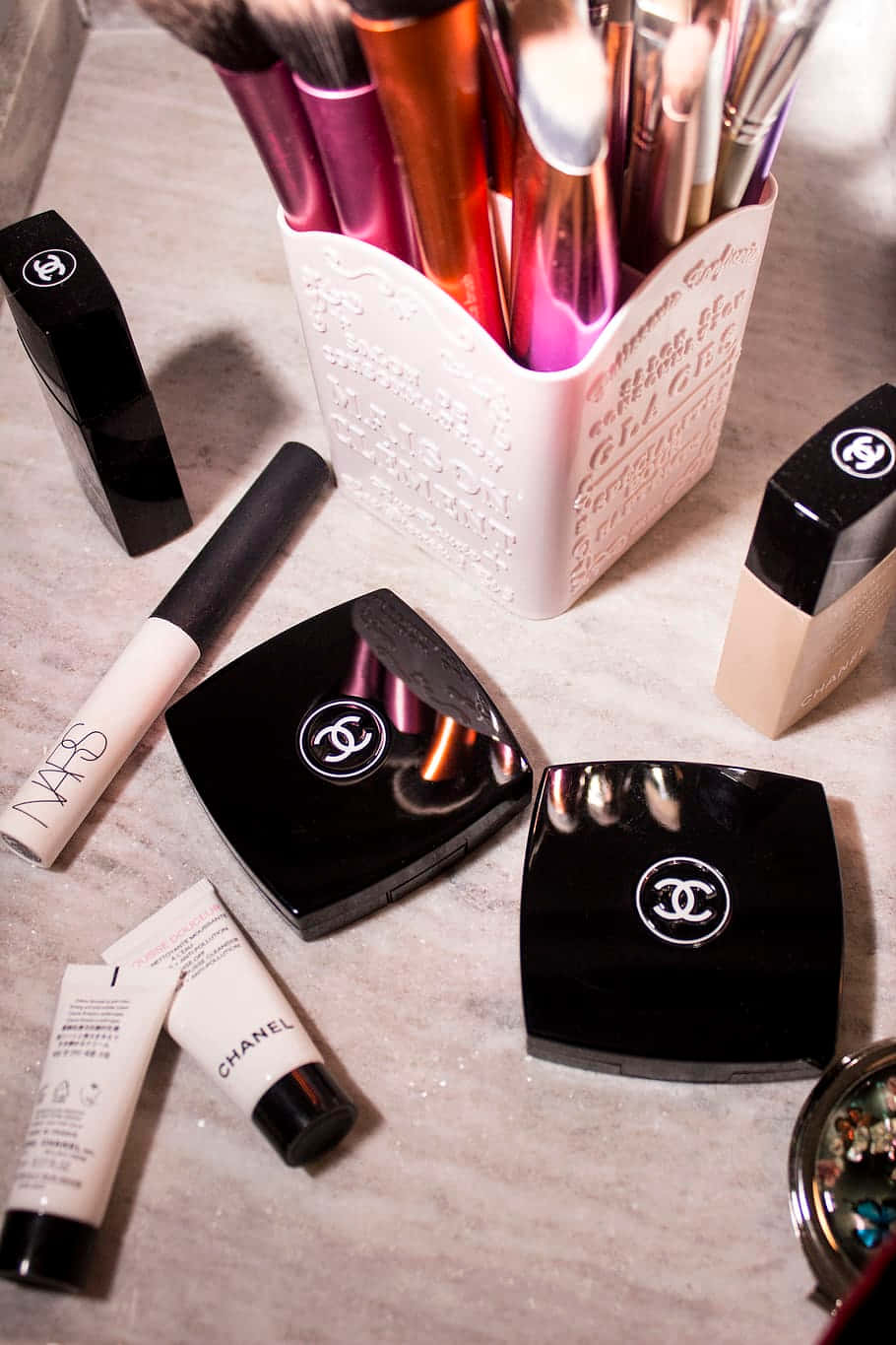 Cosmetic 桌布 壁紙 — 奢華化妝掃和Chanel化妝品在柔和溫暖的燈光下排列在大理石表面上。