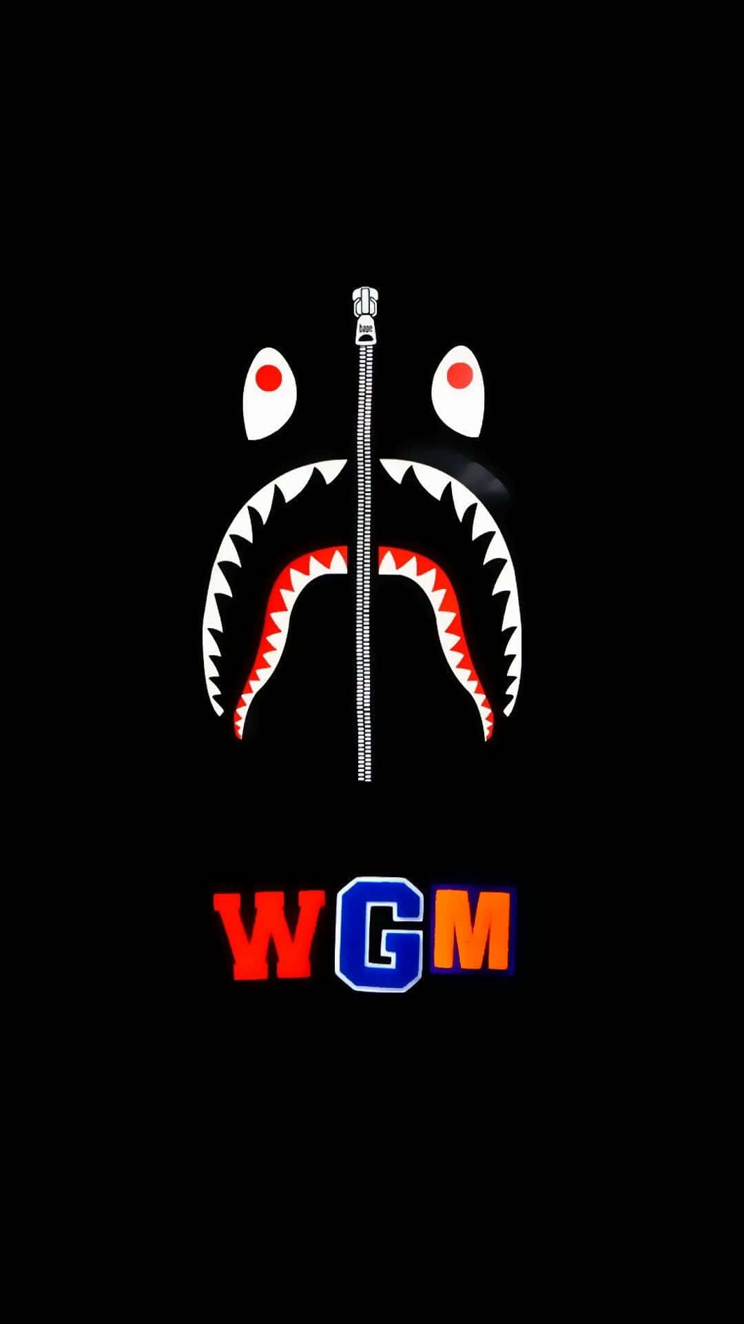 一個鯊魚臉，中間有一條拉鍊，下方有彩色WGM字母。