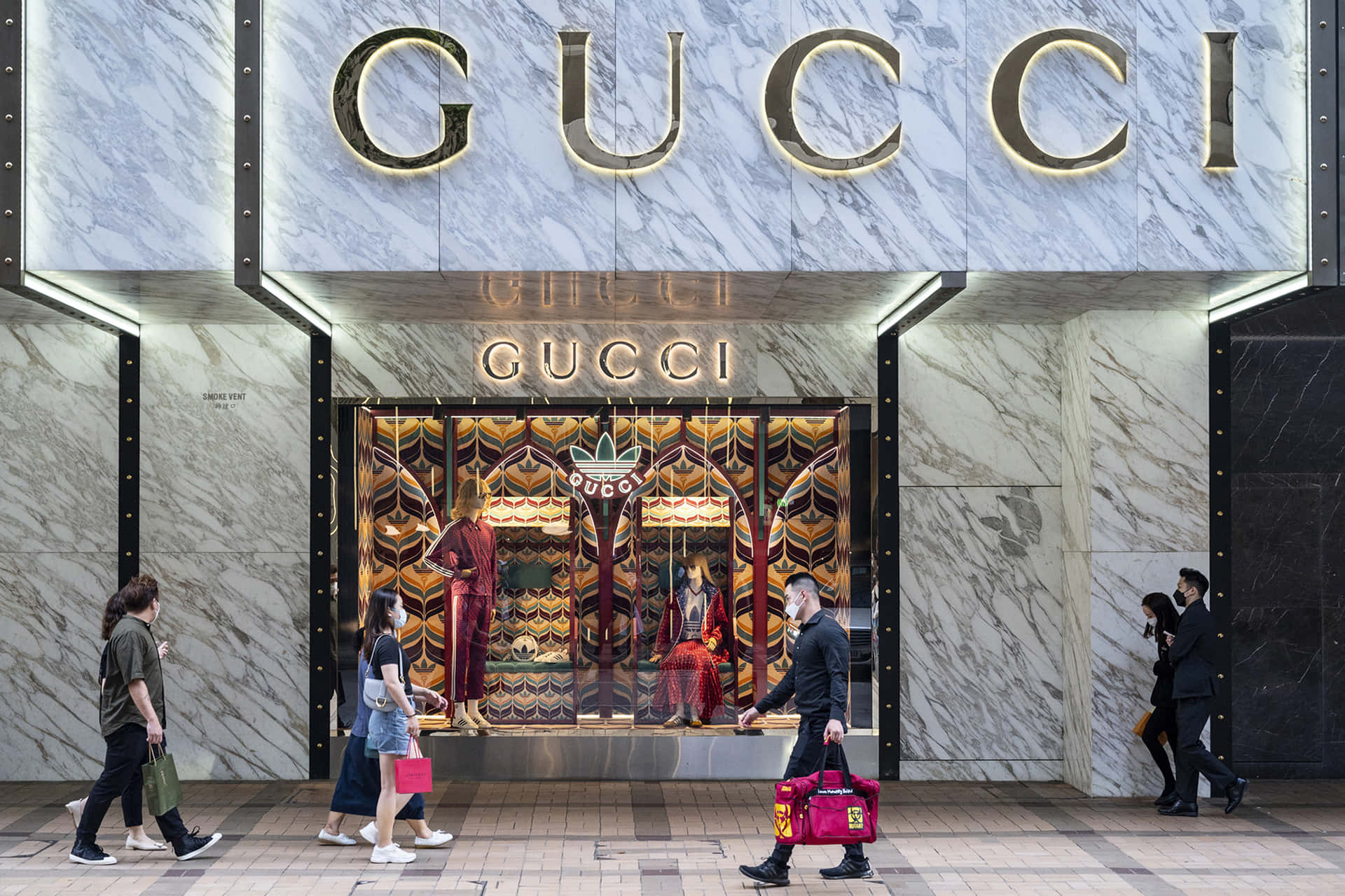 人們走過一間Gucci商店，有大理石牆壁和色彩繽紛的櫥窗展示。