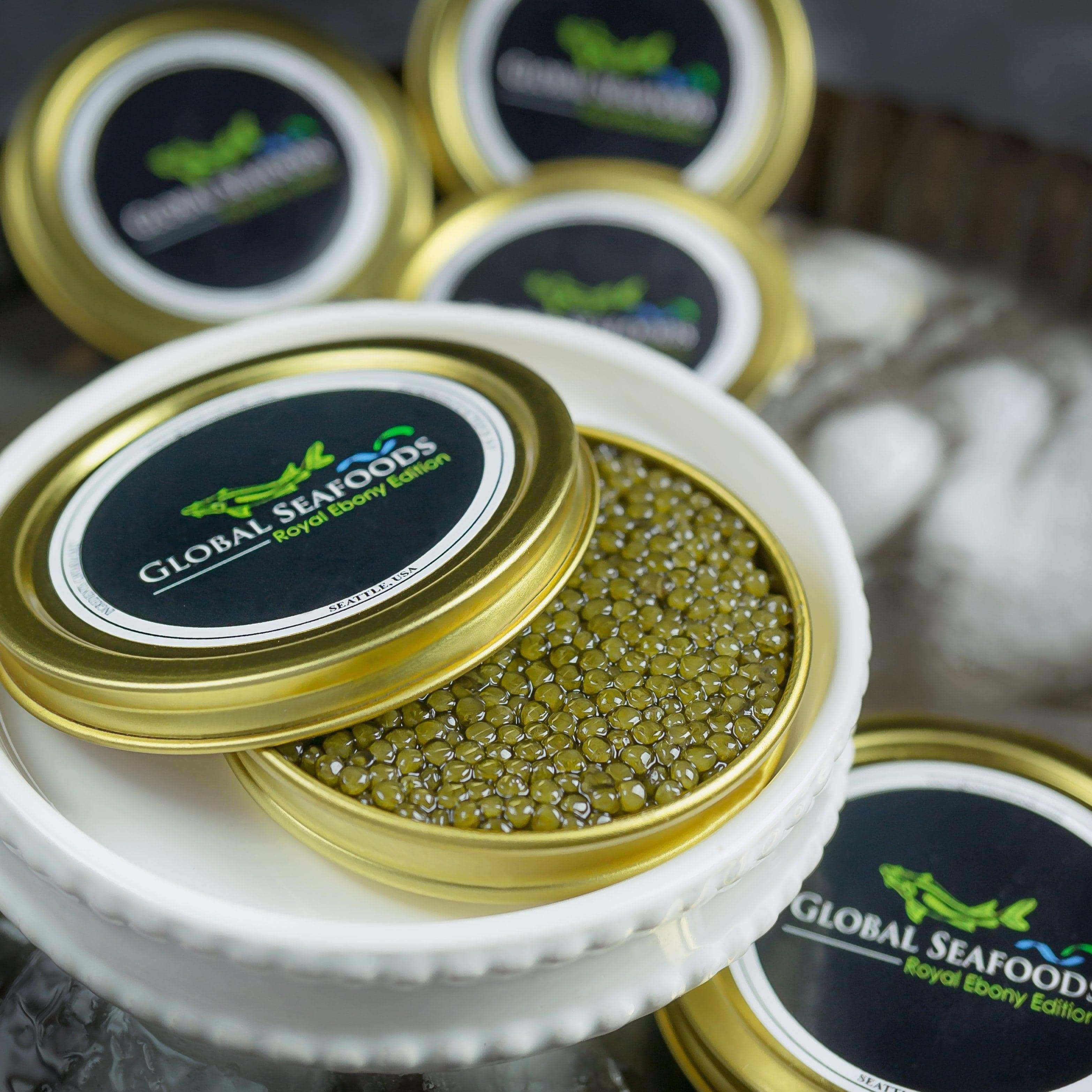 Black Caviar 桌布 壁紙 — 奢華嘅綠色魚子醬從一個金色蓋嘅罐入面流出，罐上標籤寫住 Global Seafoods Royal Ebony Edition，優雅咁擺放喺一個白色陶瓷架上。