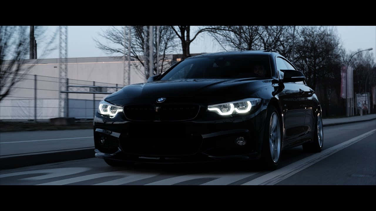 黑色BMW汽車，車頭燈明亮，在黃昏的城市街道上行駛。