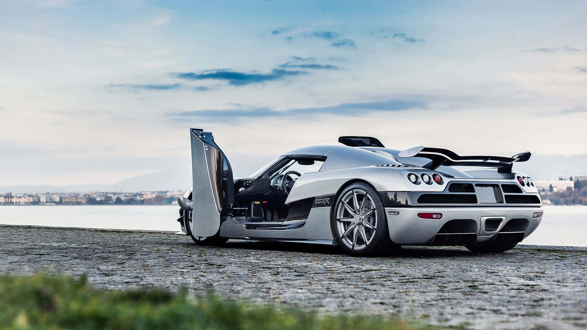 銀色Koenigsegg跑車打開車門停泊在湖邊。