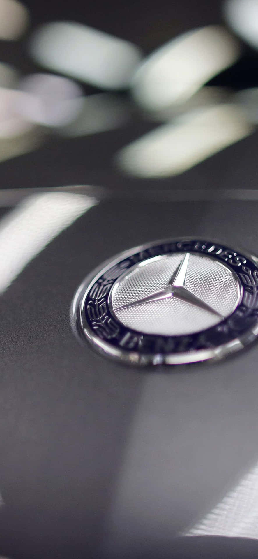 Mercedes-Benz 標誌在黑色引擎蓋上，背景模糊。