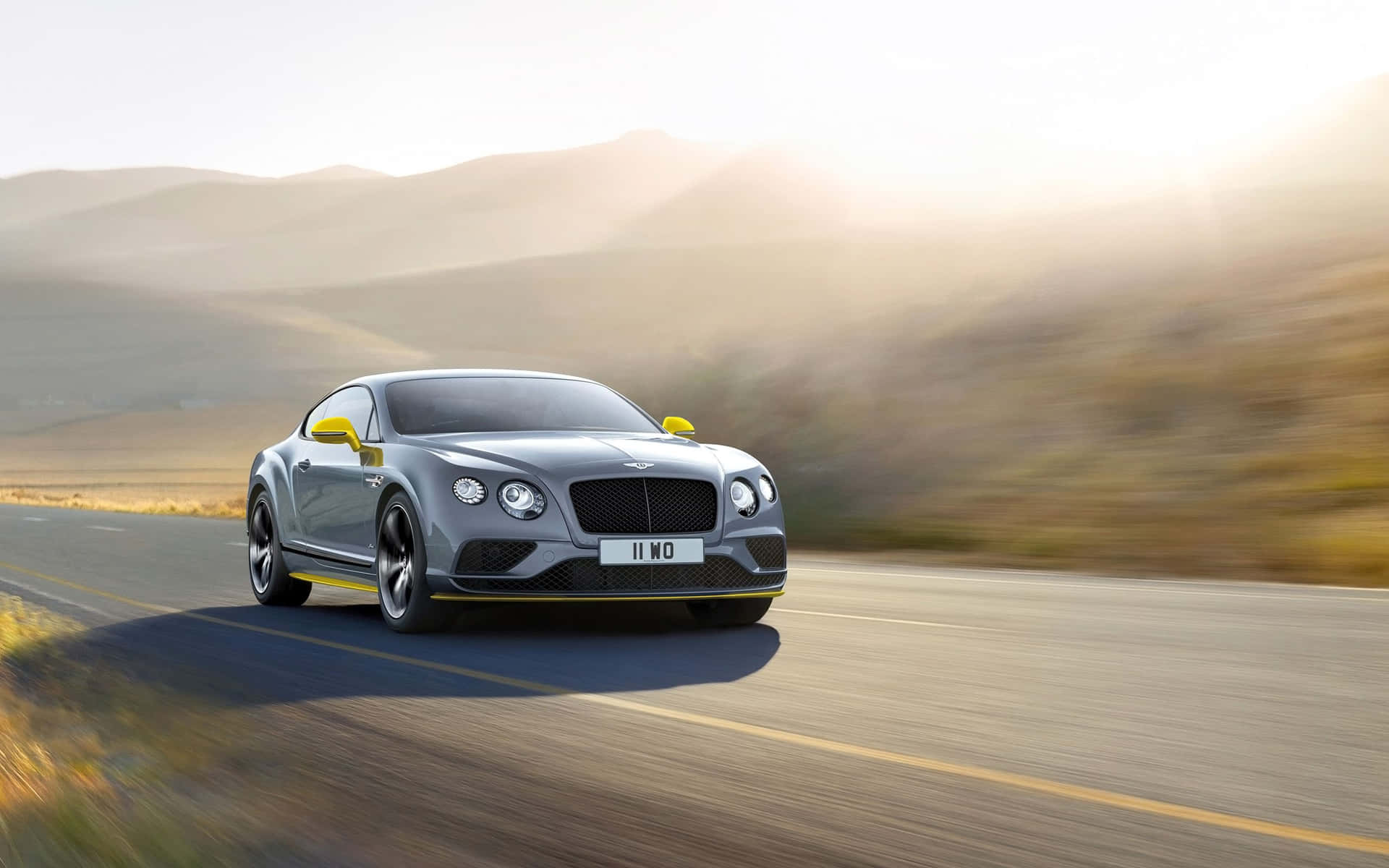 銀色賓利 Continental GT 在日出時於沙漠公路上疾馳。