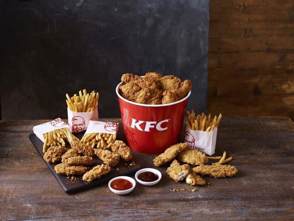 KFC炸雞和薯條放在木桌上，附有蘸醬。