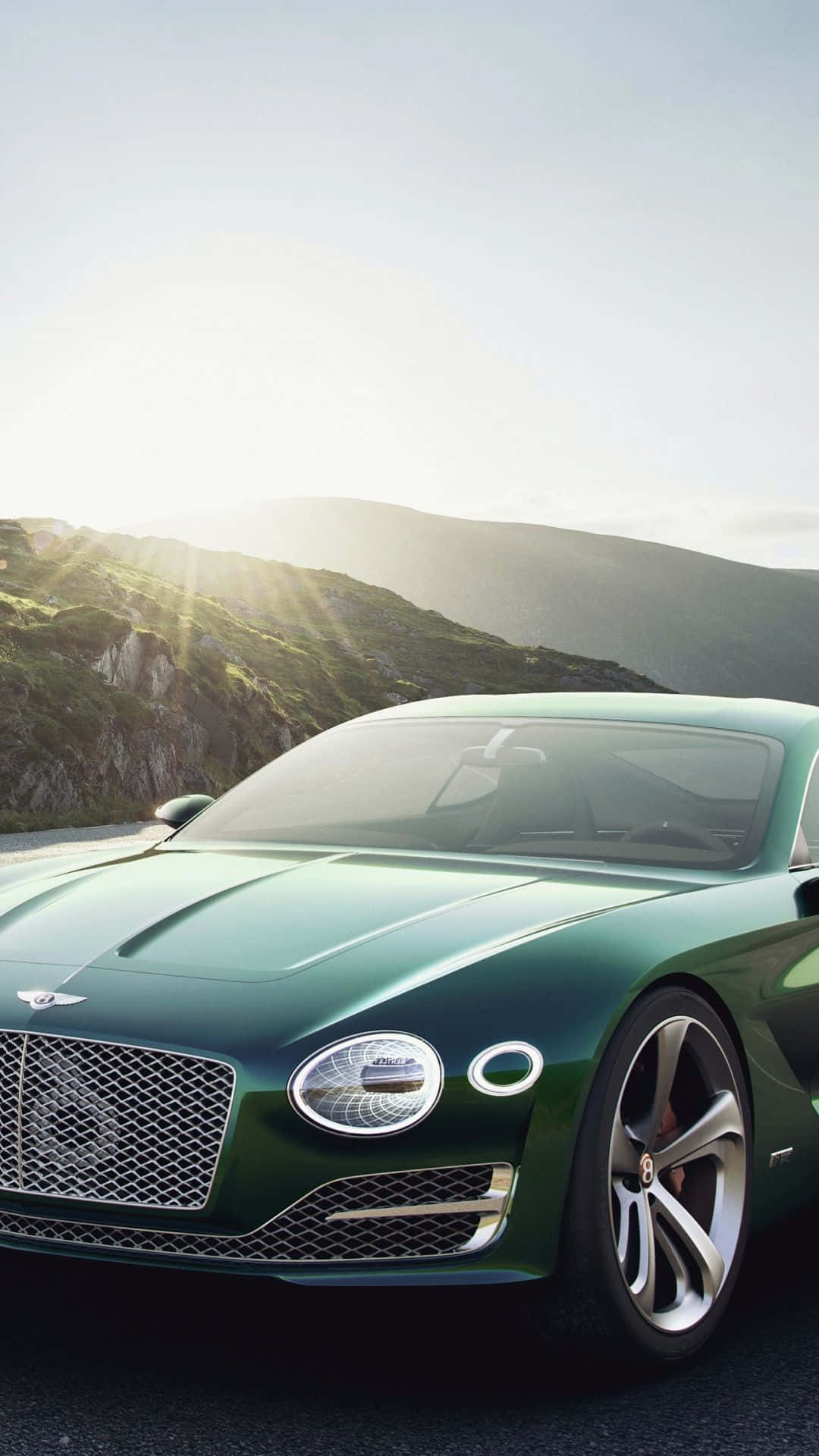 綠色賓利跑車在山路上，金色日落。