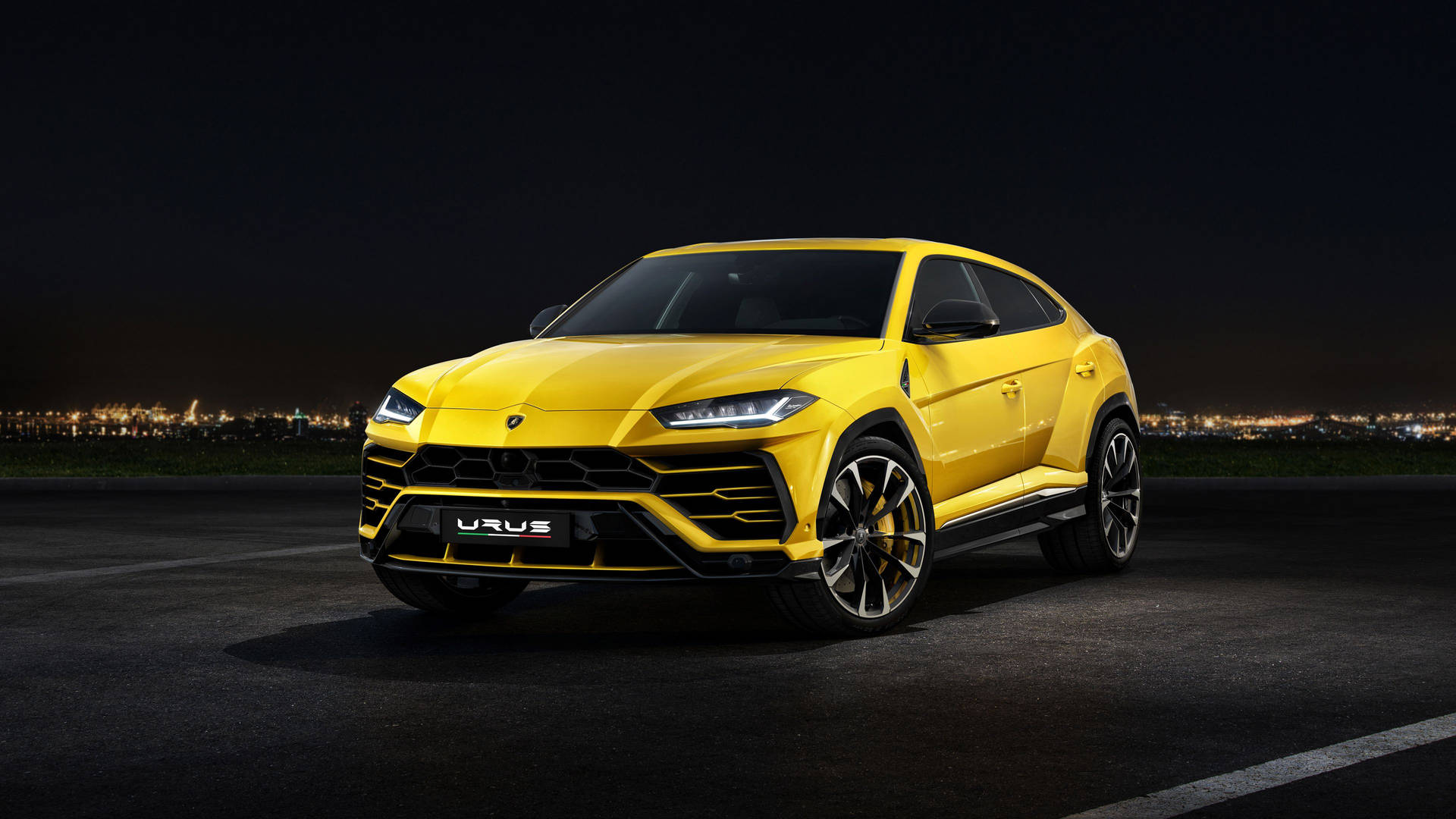 黃色林寶堅尼 Urus SUV 夜間停泊，背景有城市燈光。