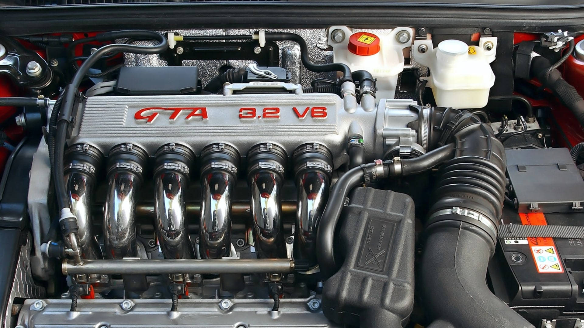 銀色 V6 汽車引擎的特寫，帶有紅色字樣和鍍鉻部件。