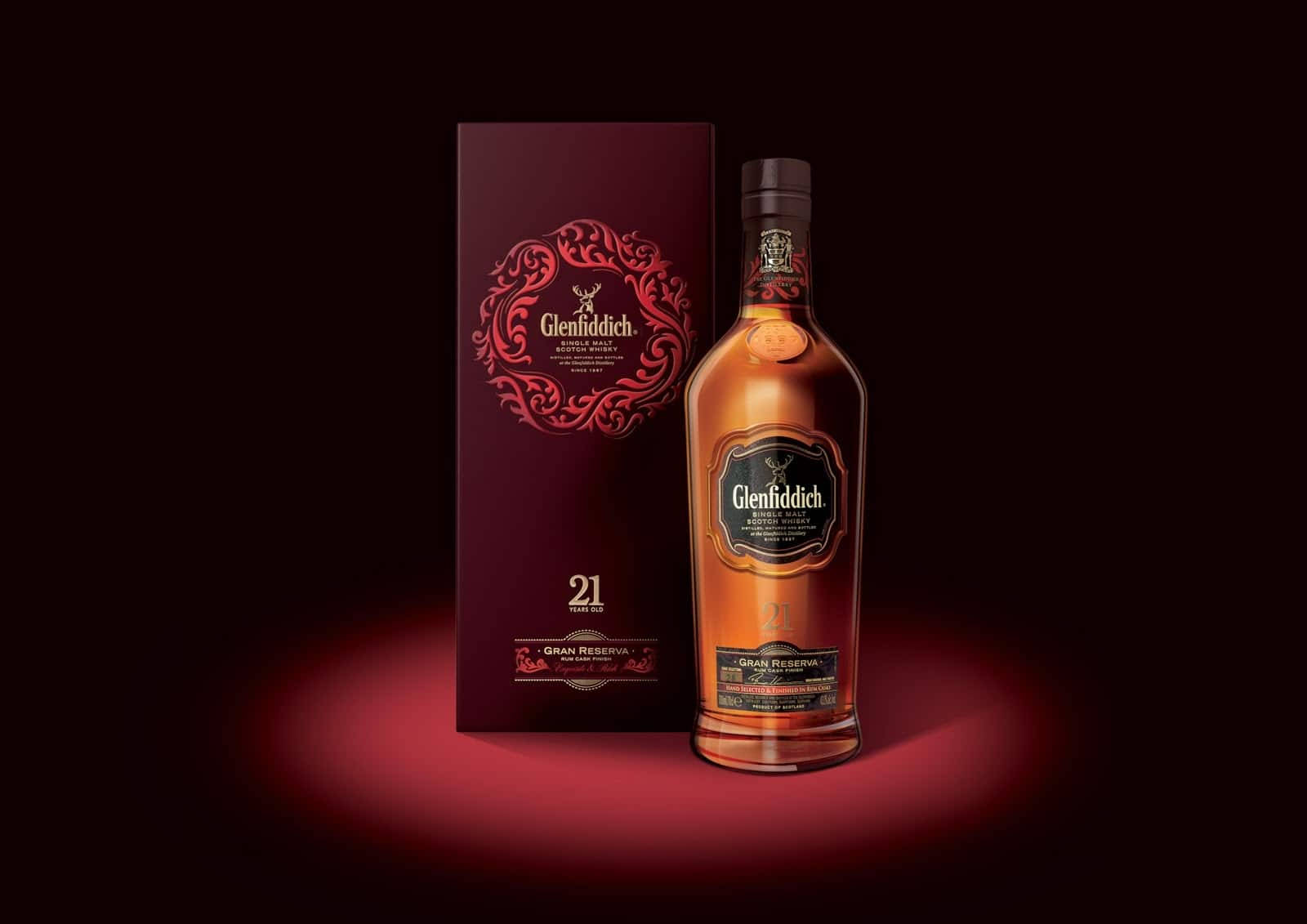 Glenfiddich 21 年威士忌酒瓶和盒子在紅光中照亮。