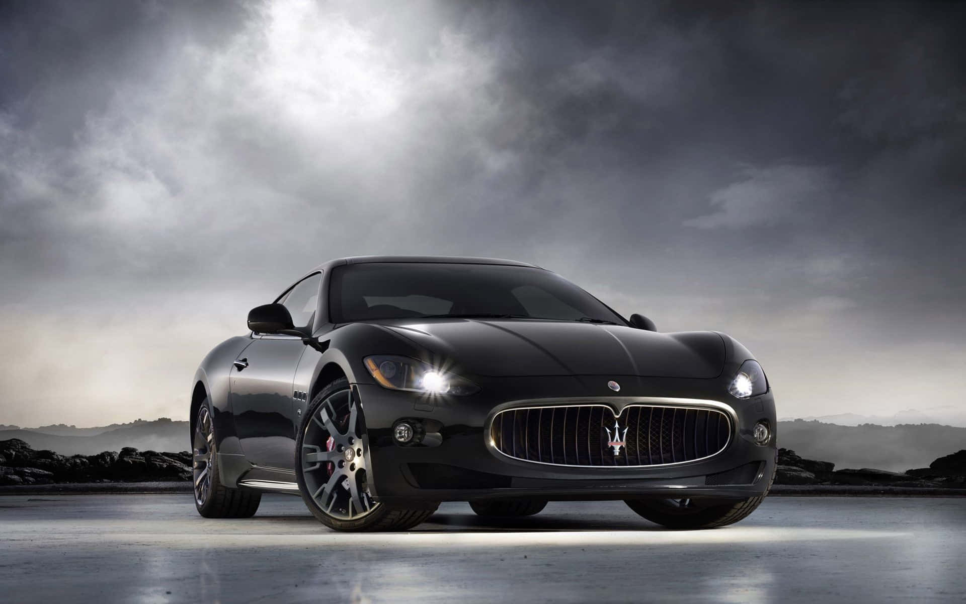 暴風天空下黑色Maserati跑車亮著車頭燈。