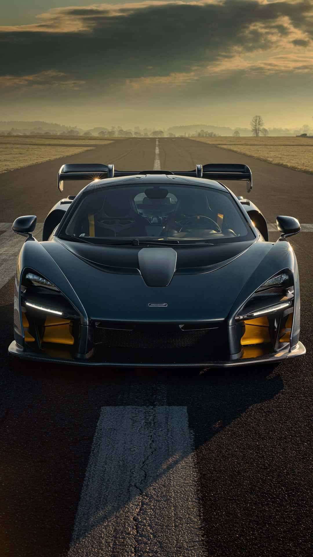 金色黃昏時分，黑色McLaren Senna跑車停在跑道上。