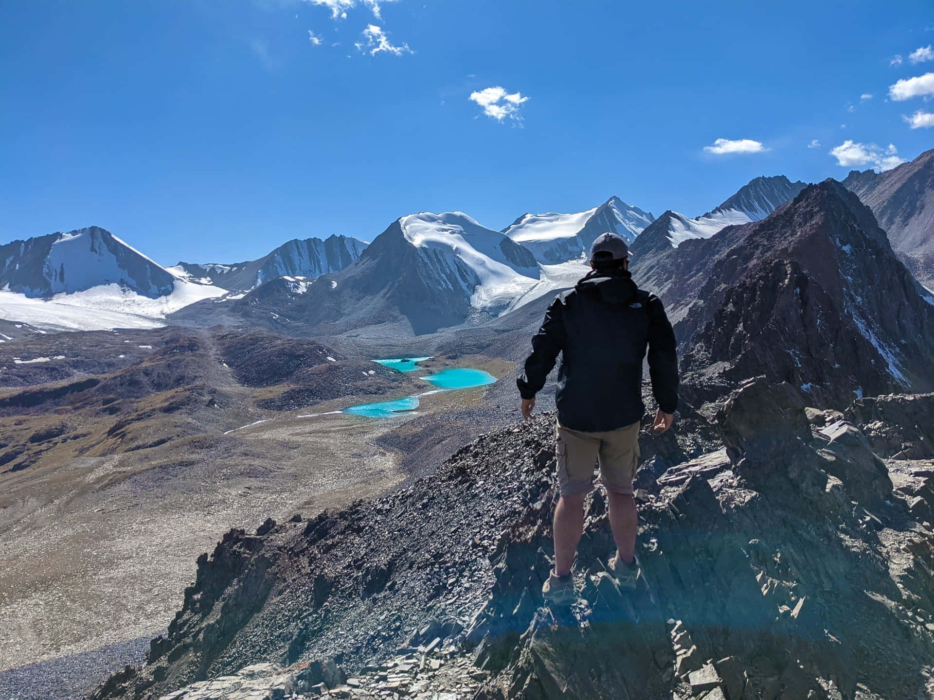 遠足者站在山脊上俯瞰白雪覆蓋的山峰和碧綠湖泊