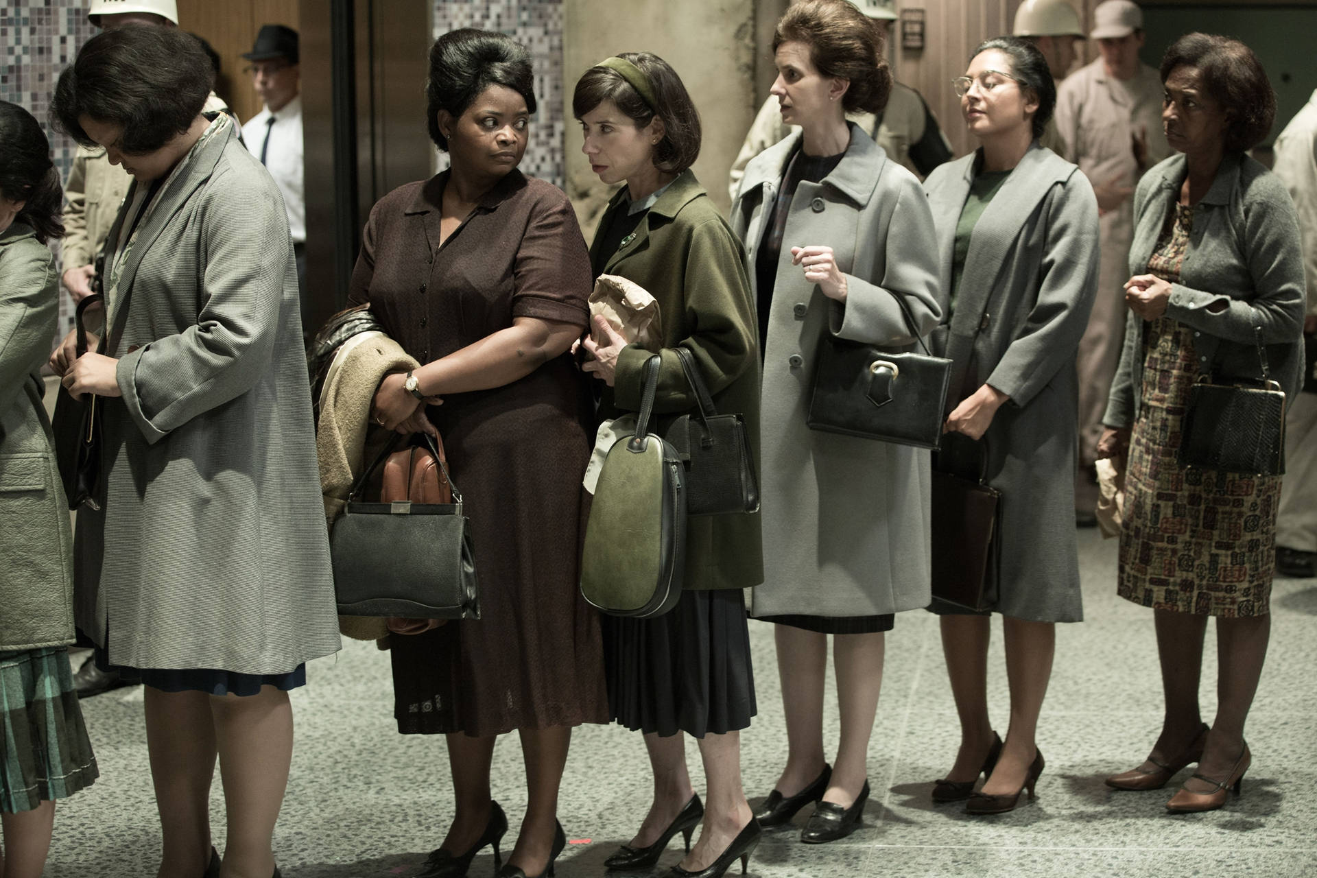 穿著1960年代大衣和高跟鞋的女性，帶著嚴肅的表情在室內排隊站立。