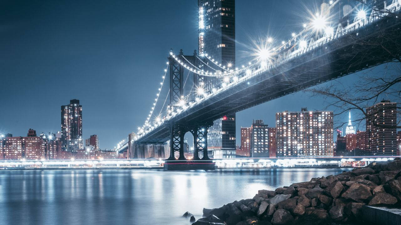 奧克蘭天際線的日落美景 壁紙 — 曼哈頓大橋在水面上的迷人夜景，城市燈光倒映，橋上閃爍的星星。
