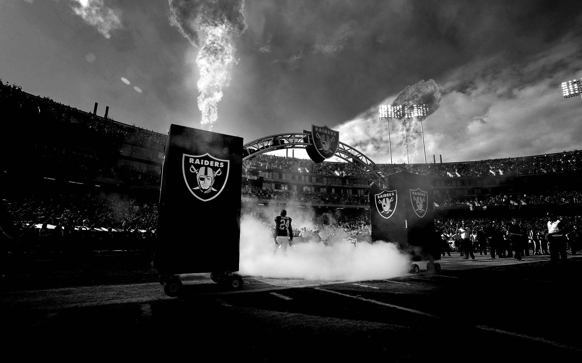 Raiders 美式足球運動員在夜間體育場穿過煙霧