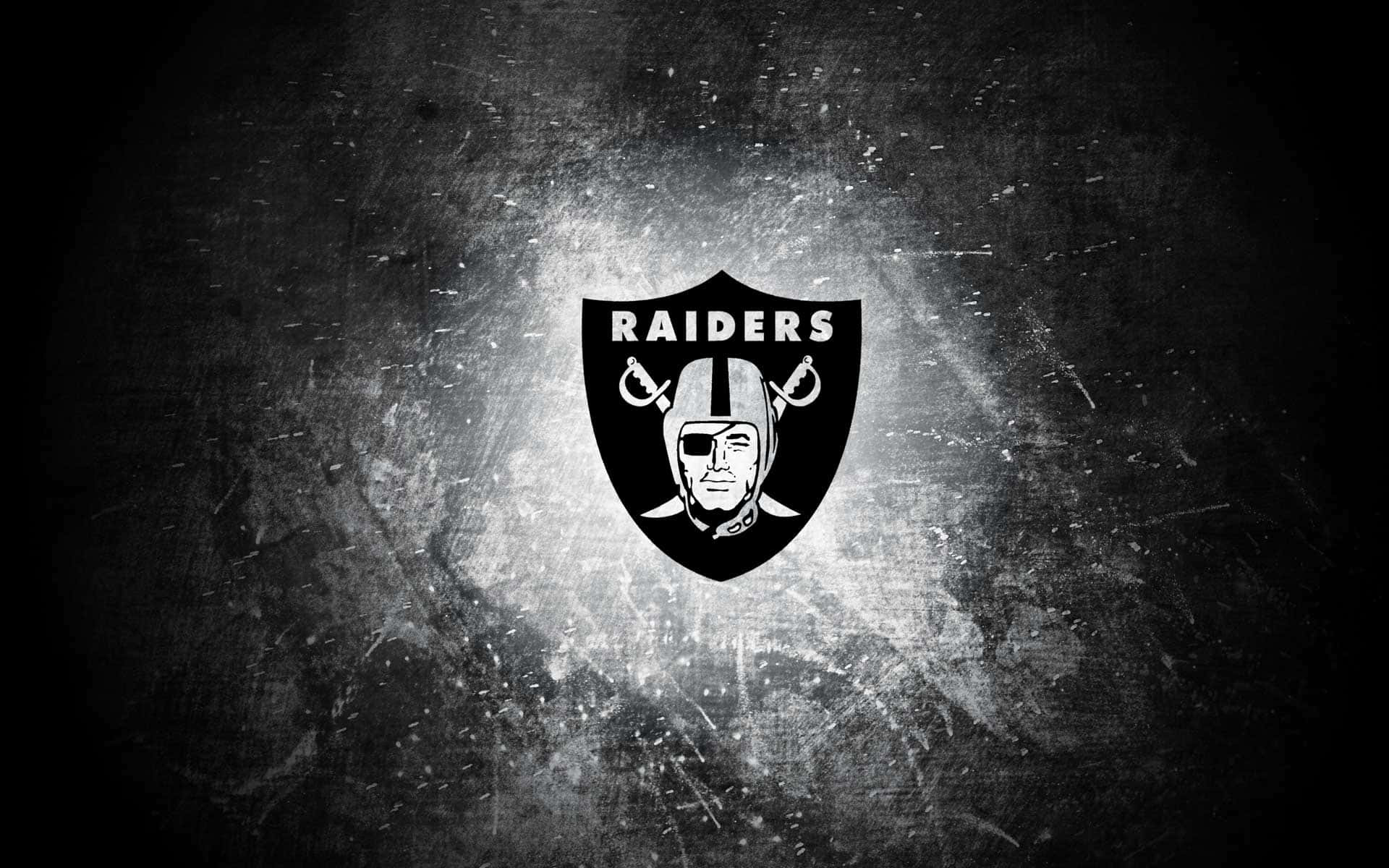 奧克蘭突襲者黑白標誌 壁紙 — 一個大膽的黑白Raiders標誌在帶有光紋的粗糙紋理背景上發光。