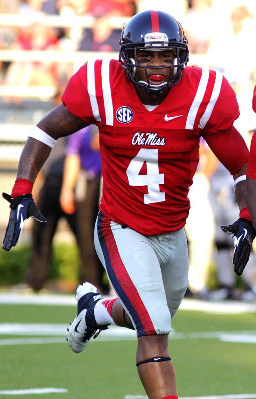 身穿紅色 Ole Miss 制服的美式足球員在草地上奔跑。