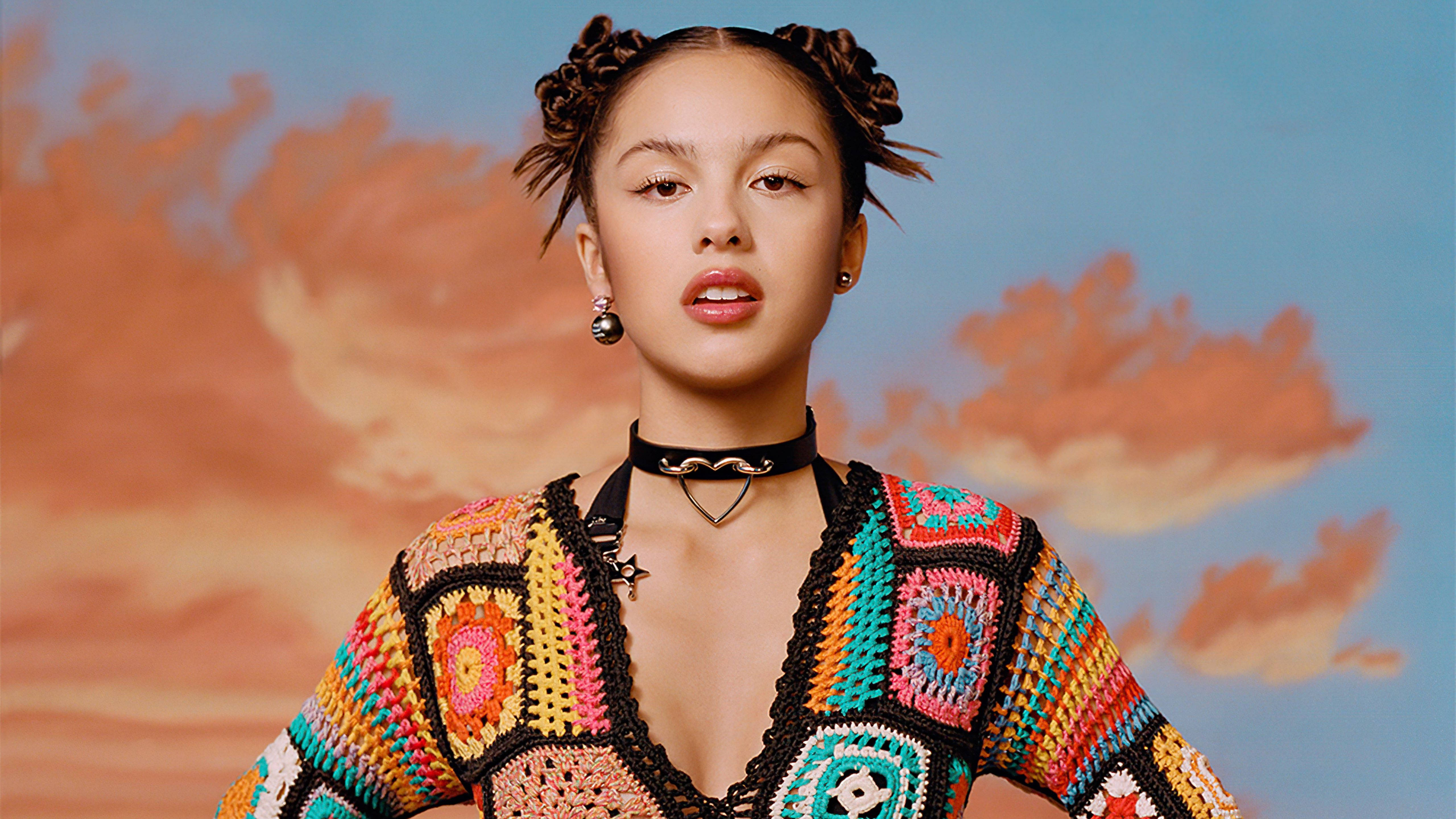 奧利維亞·羅德里戈《Variety》2021封面 壁紙 — 一位年輕女子編著辮子，穿著色彩繽紛的鉤針上衣，背景是彩繪天空。