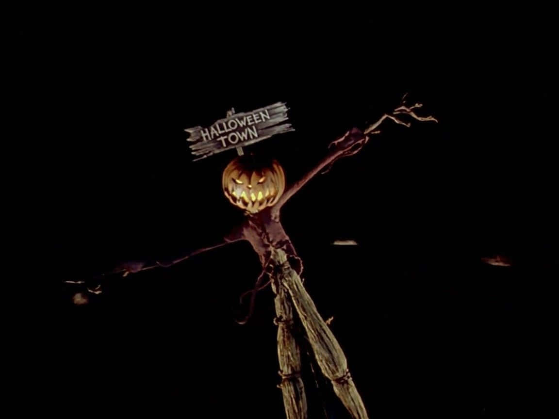 發光的傑克南瓜燈稻草人在黑暗中舉著Halloween Town標牌。
