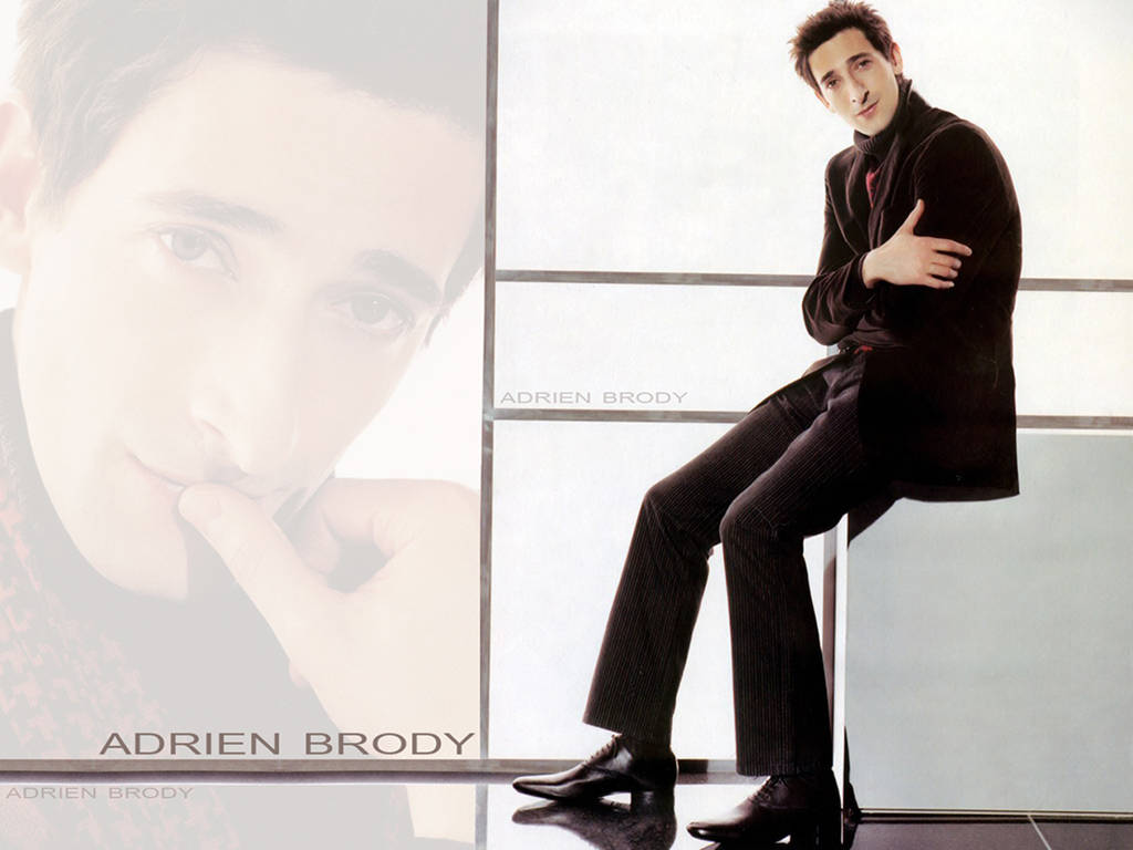 奧斯卡得主阿德里安·布洛迪展現帥氣與沉思神情 壁紙 — Adrien Brody 身穿深色西裝，自信地站在明亮的窗戶前，帶有褪色肖像疊加效果。