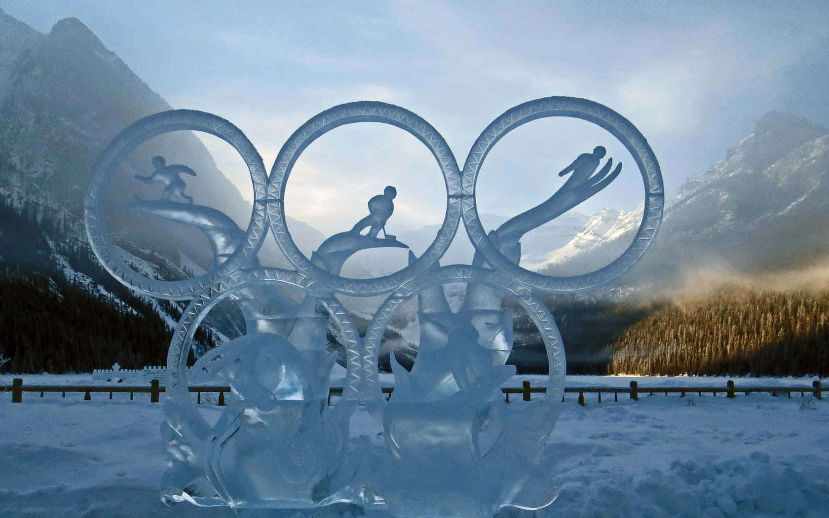 Ice Sculpture 桌布 壁紙 — 奧林匹克五環的冰雕，冬季運動員的剪影映襯著雪山和森林。