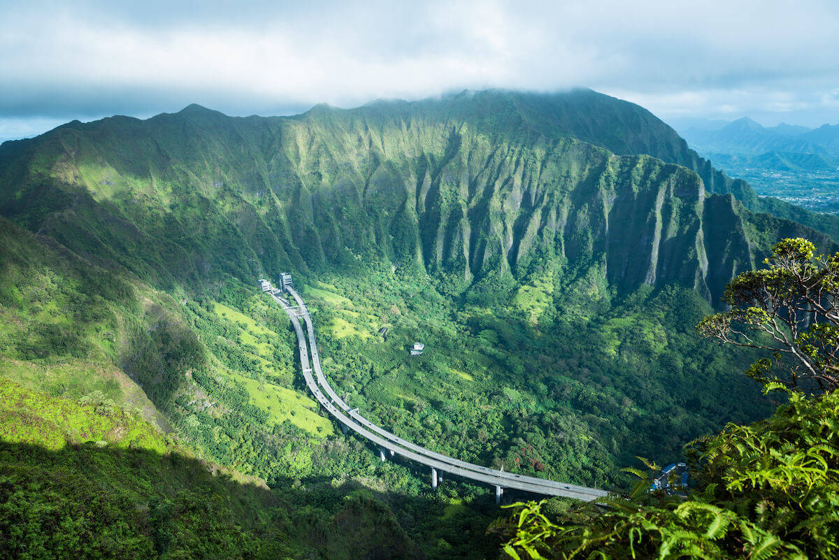 奧胡島高速公路空中俯瞰 壁紙 — 一條蜿蜒的高速公路在陰天之下，蜿蜒穿過鬱鬱蔥蔥的綠色山谷。