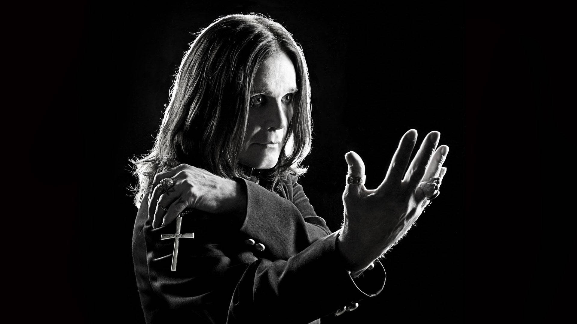 Ozzy Osbourne 黑白照片，帶十字架和戒指，背景深色。