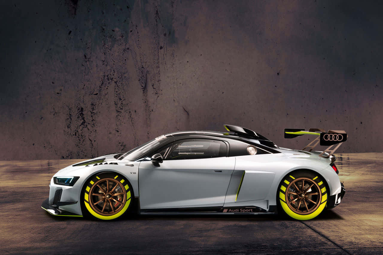 奧迪R8——高性能宣言 壁紙 — 一架型格銀色奧迪R8 LMS GT3賽車，帶有螢光黃色點綴和青銅輪圈，停在紋理混凝土牆前。