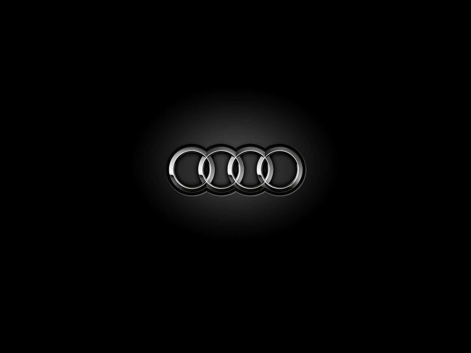 Logo 桌布 壁紙 — 奧迪標誌帶有四個相扣的圓環，在聚光燈下於純黑背景上閃耀。