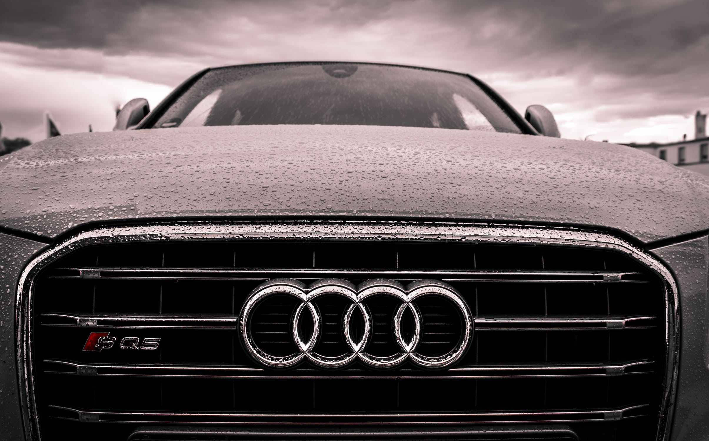奧迪車頭特寫 壁紙 — 暴風雨天空下，濕潤的Audi SQ5鬼面罩特寫，引擎蓋上雨滴閃爍。