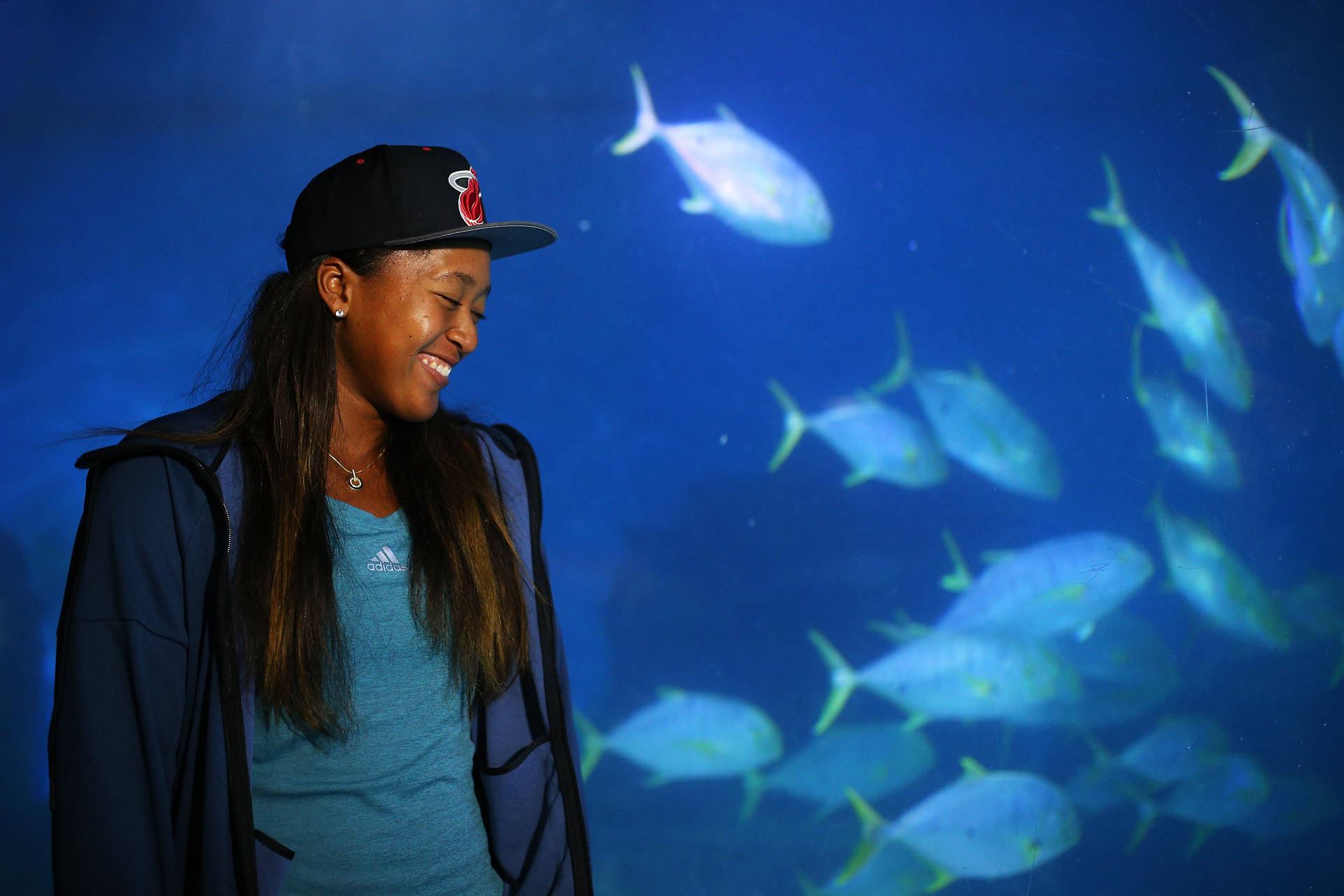 女士微笑著觀看魚在水族箱中游泳。