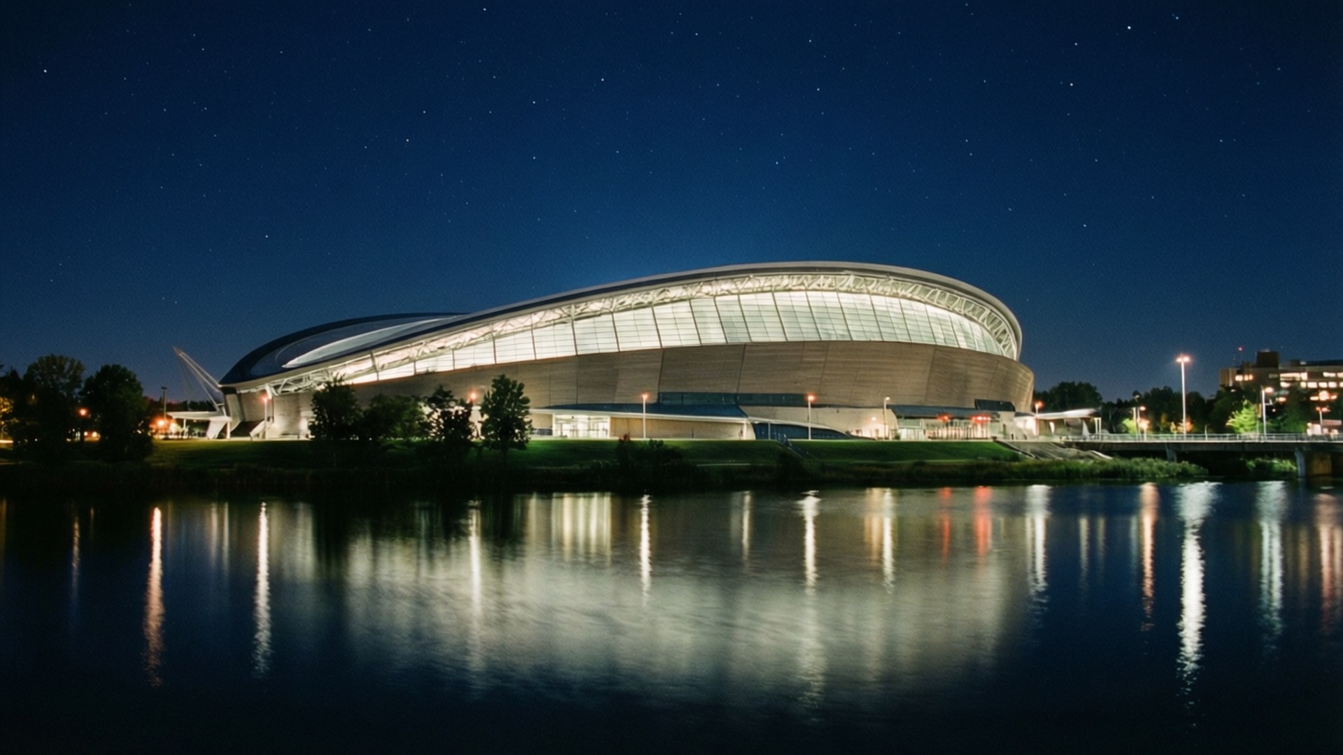 夜晚燈火通明的現代化體育場，星空與水面倒影。